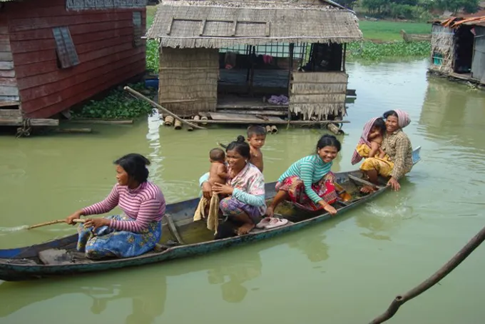 Kvinner og barn padler i en kano i Kambodsja