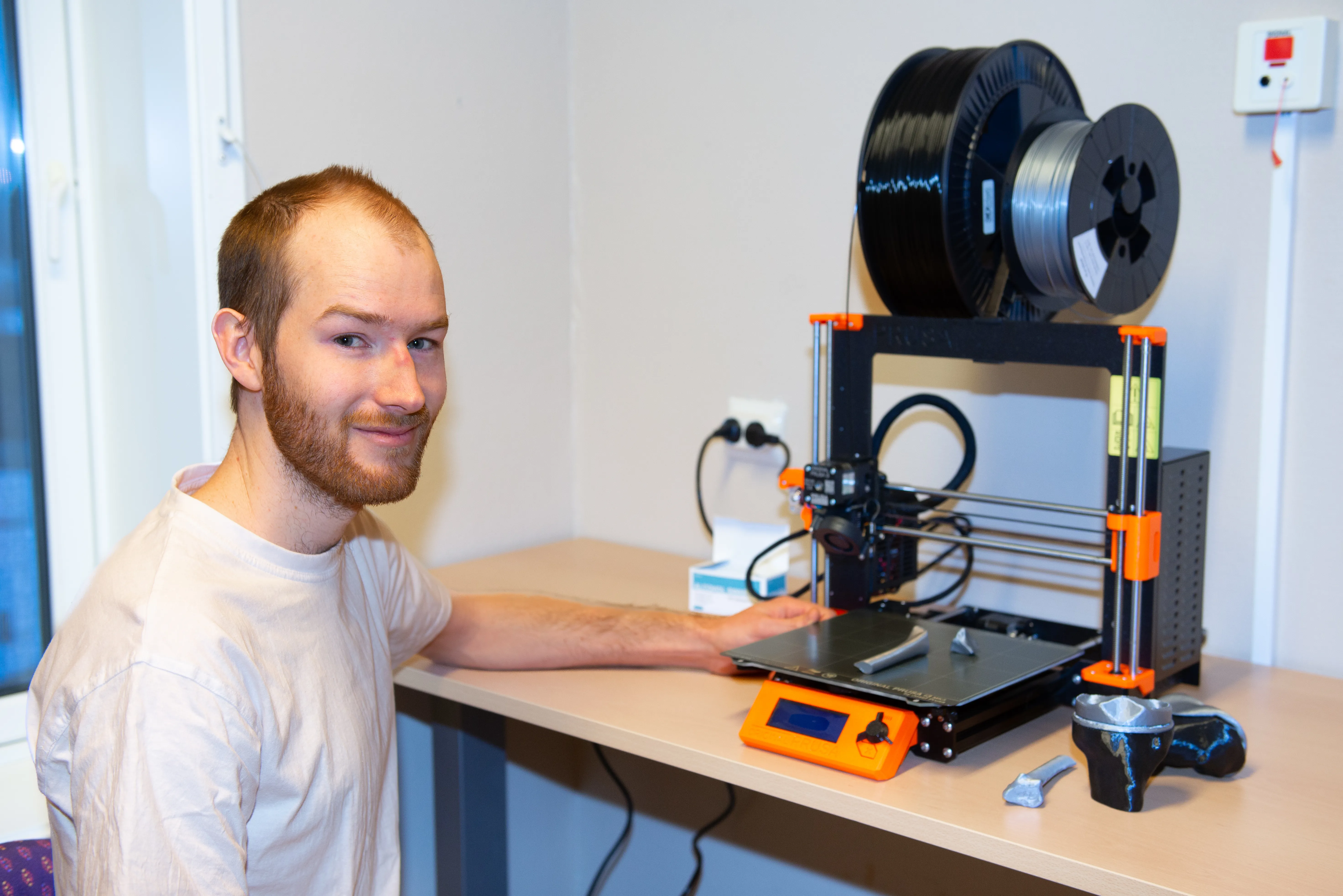 Ung mann i hvit -skjorte foran en 3D-printer