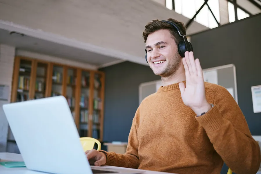 Mann som hilser mot en pc-skjerm