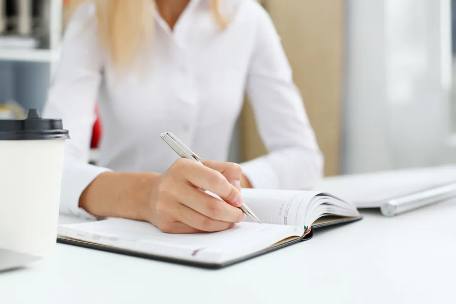 En kvinne som skriver på et stykke papir