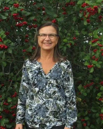 En person som står foran en busk med røde blomster