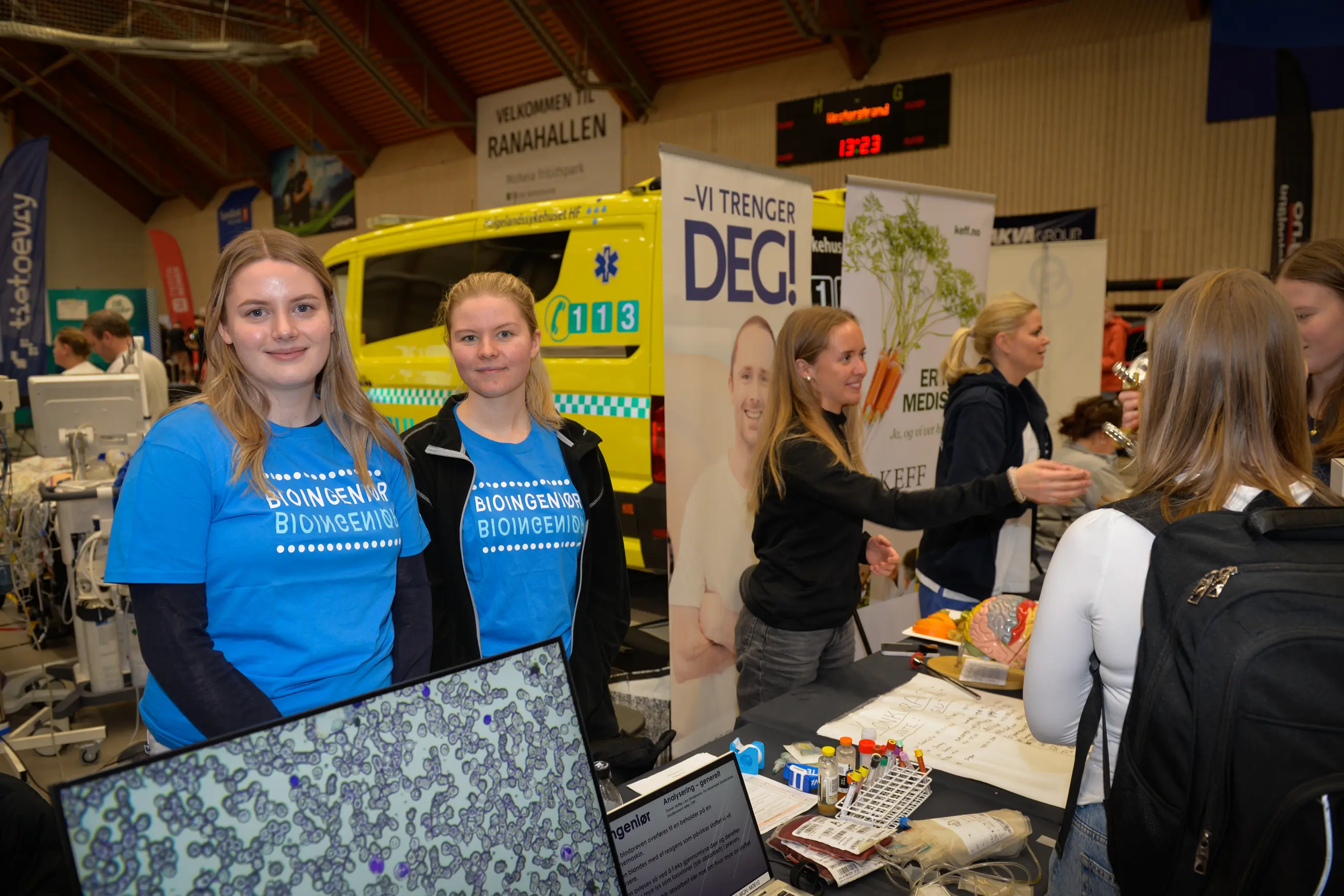 To damer smiler mens de står bak et bord