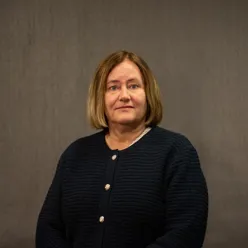 Dame med mørkt hår poserer for et portrett mens hun ser inn i kamera