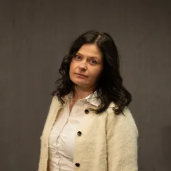 Dame med mørkt hår poserer for et portrett mens hun ser alvorlig inn i kamera