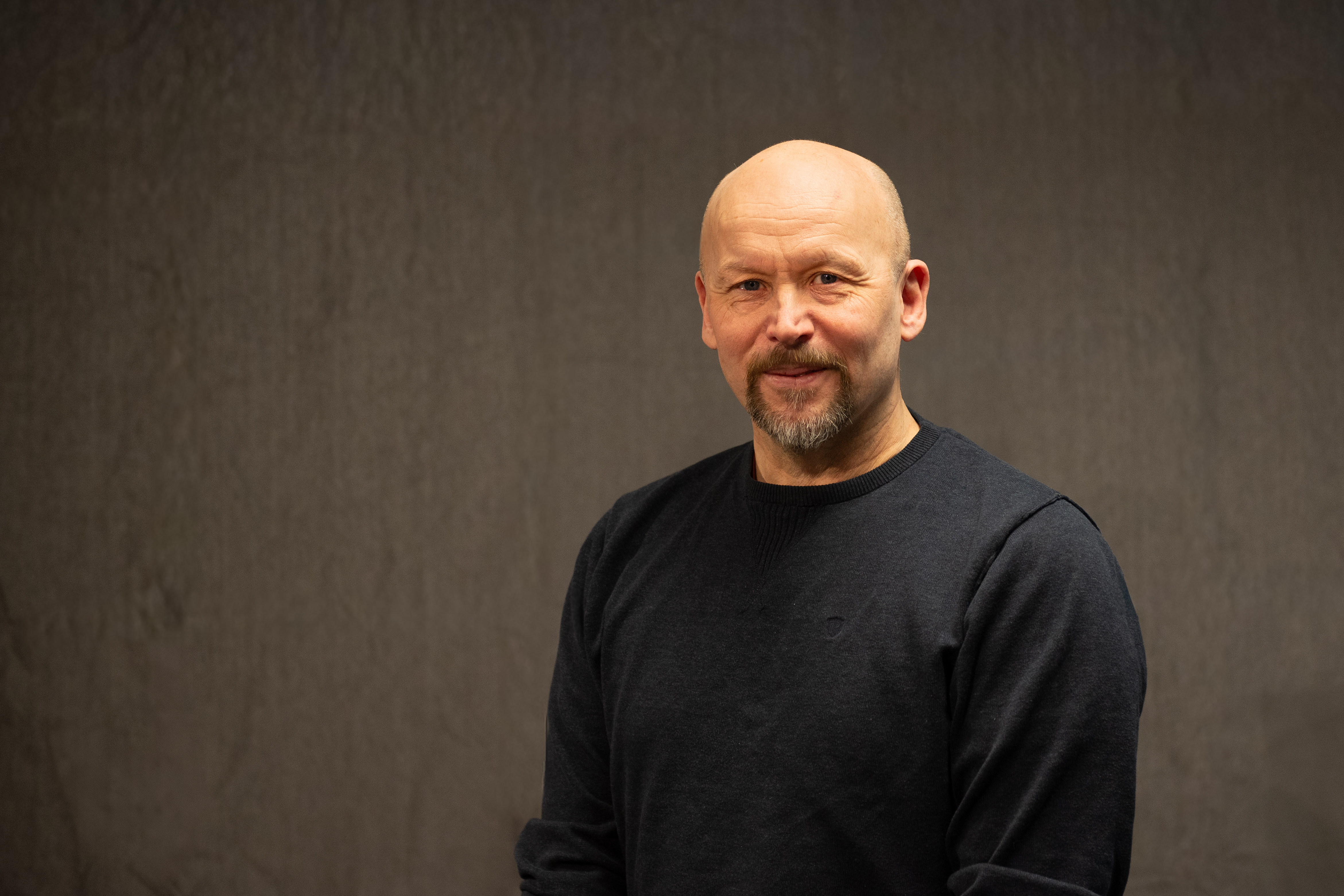 Mann med skjegg og bart poserer for et portrett mens han ser inn i kamera