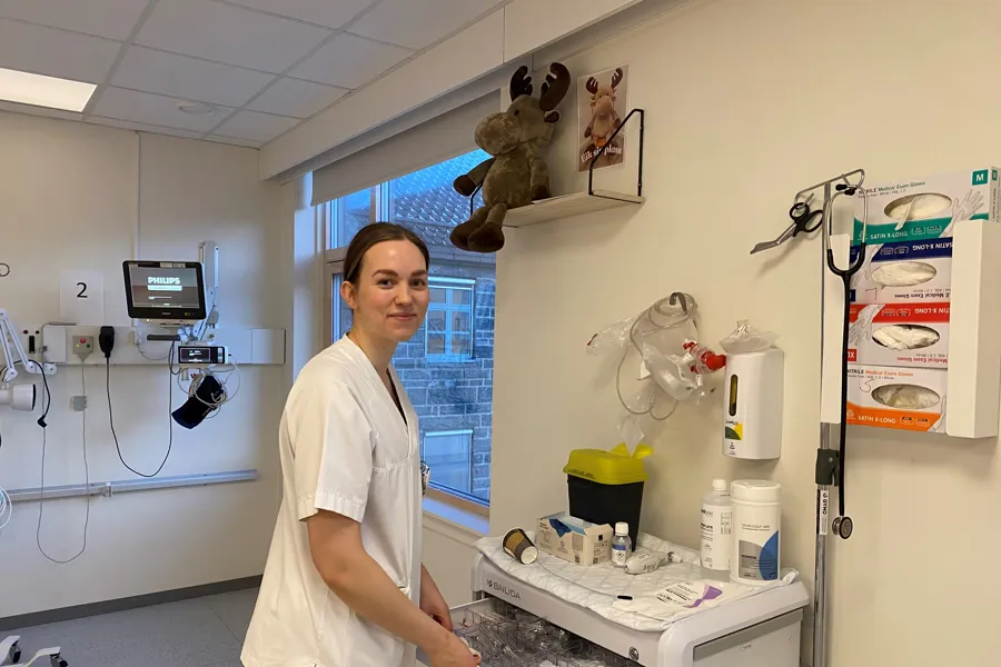 En person i sykehusklær som står ved siden av en maskin