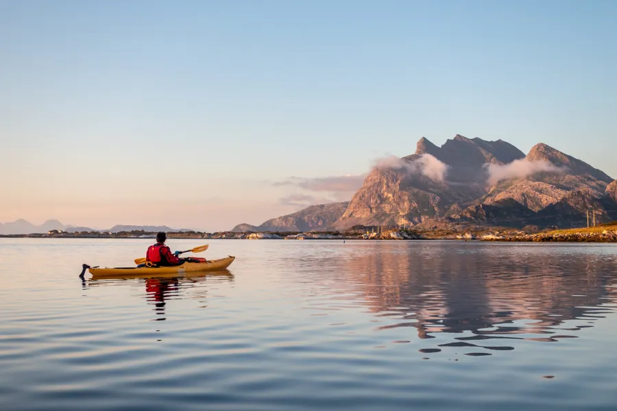 En person i en kano på en innsjø med Dønnafjellet i bakgrunnen
