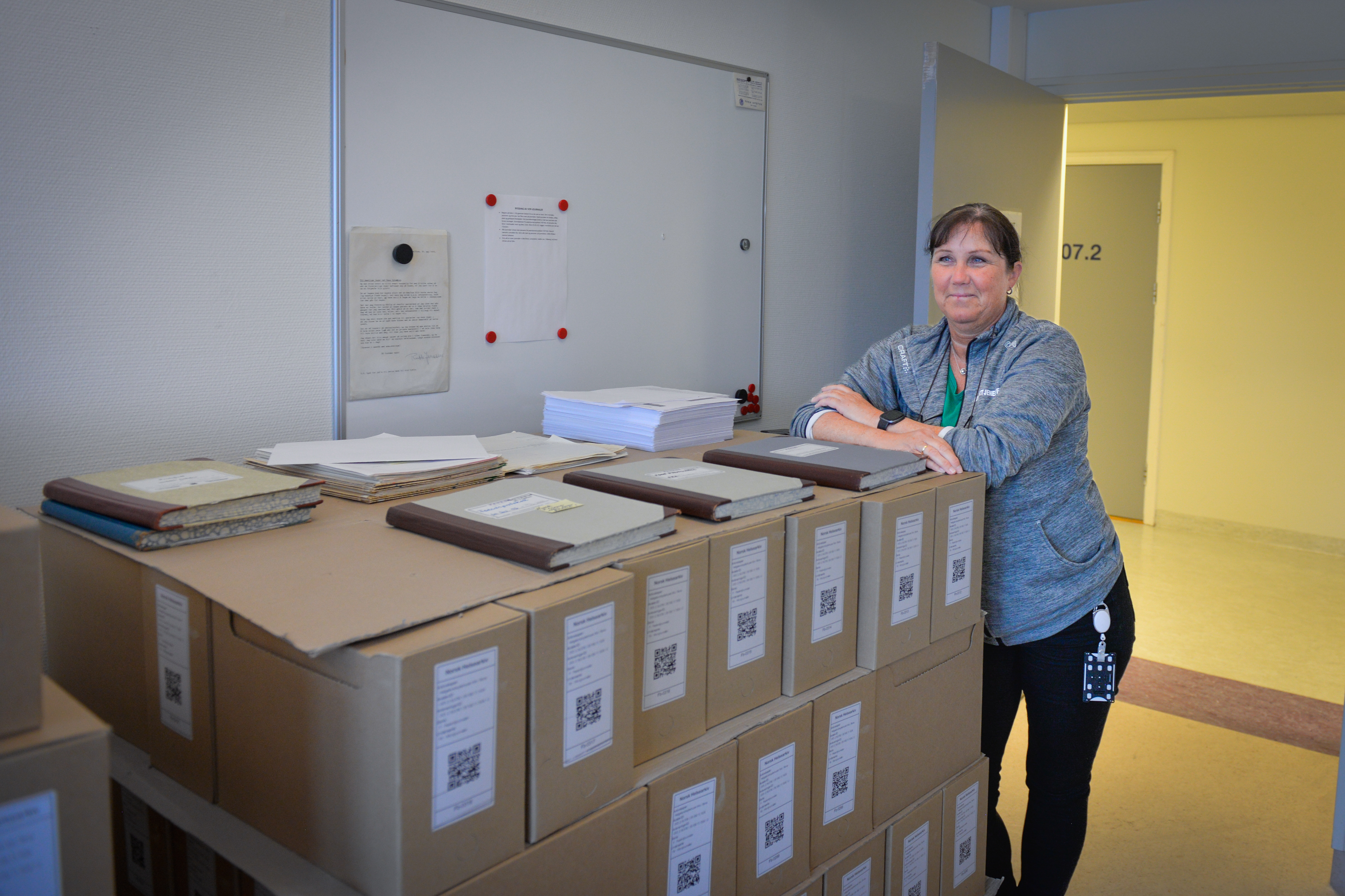 Dame lener seg på en pall full av pappesker