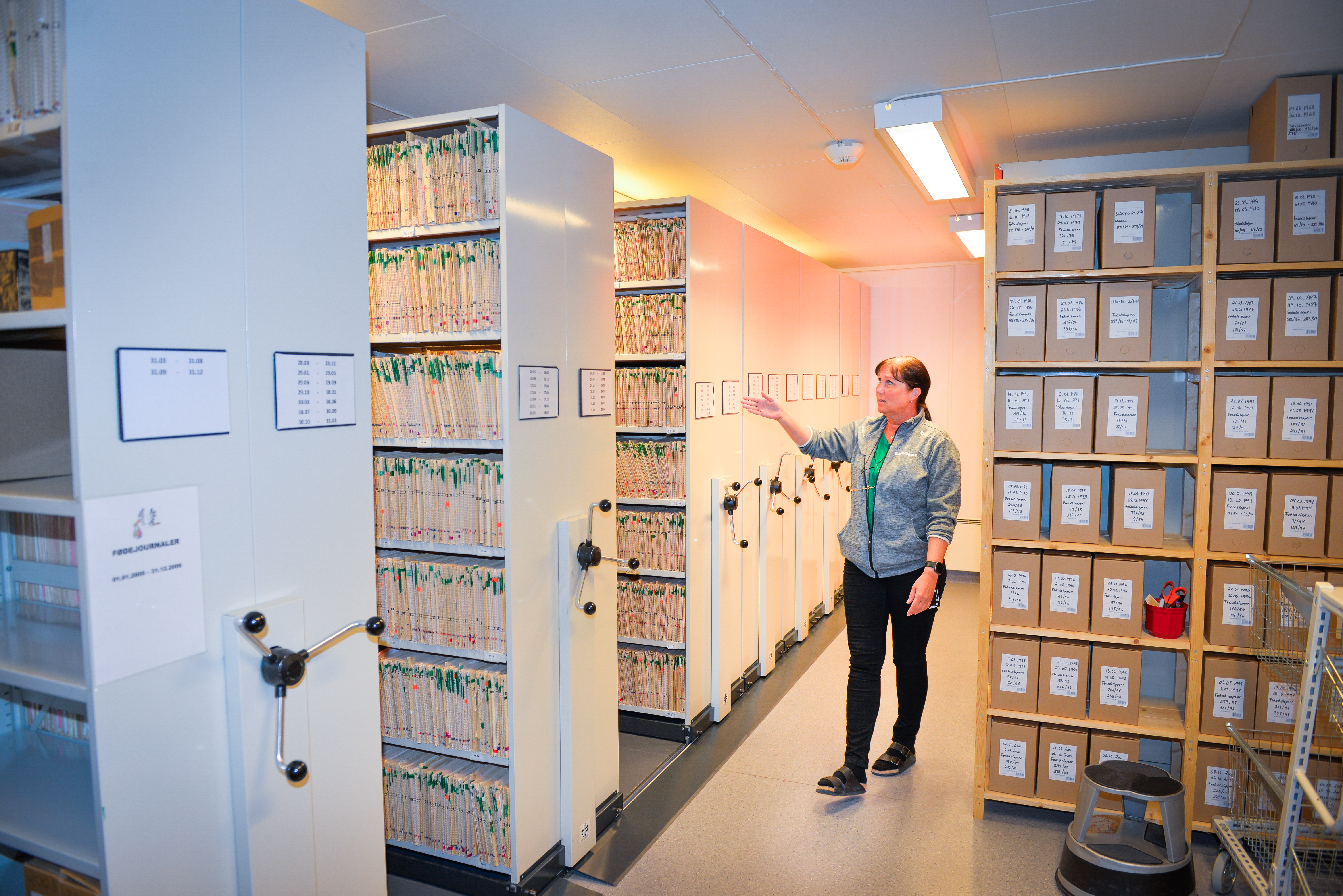 Dame står i et arkivrom med mange reoler