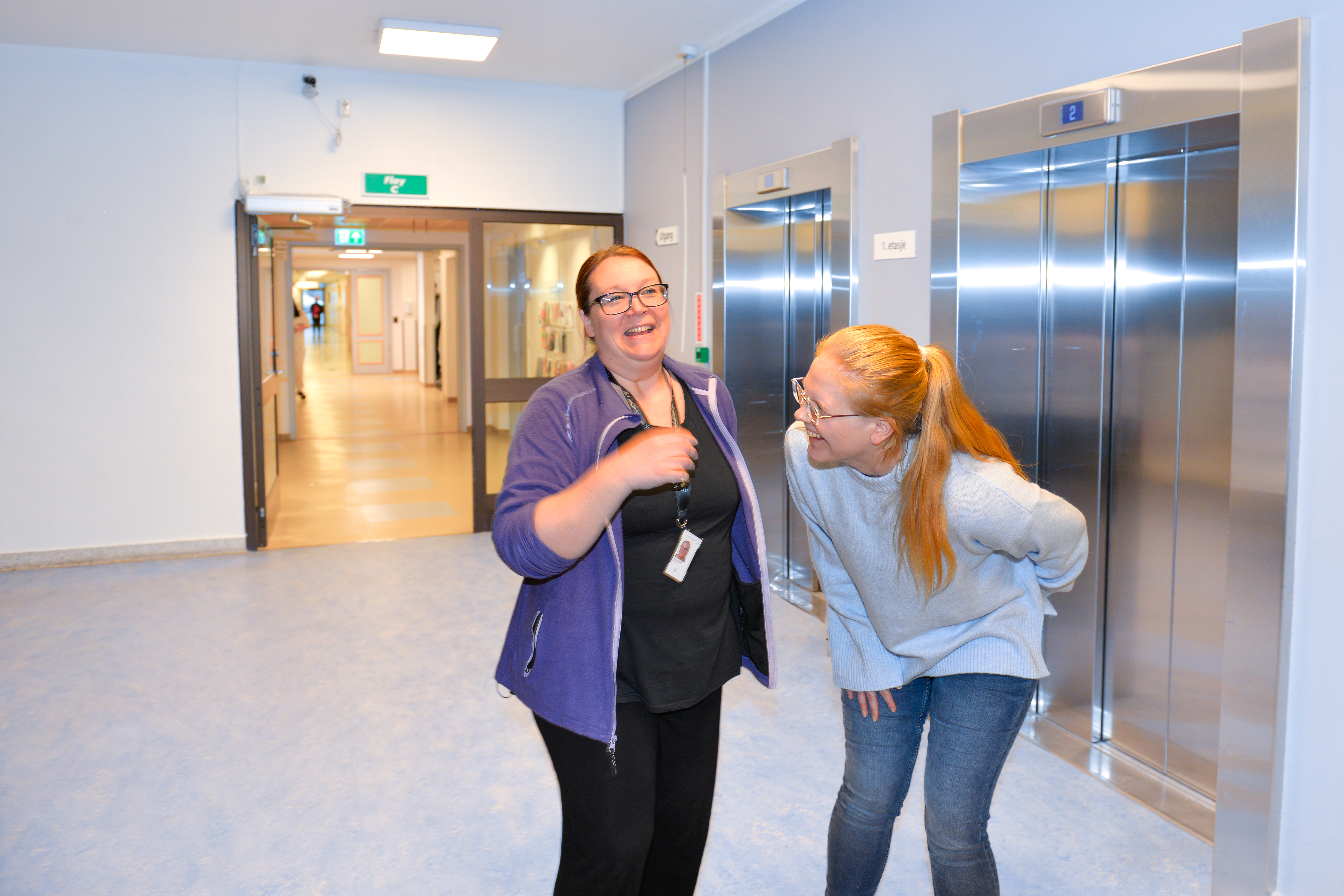 To damer som ler i en sykehusgang
