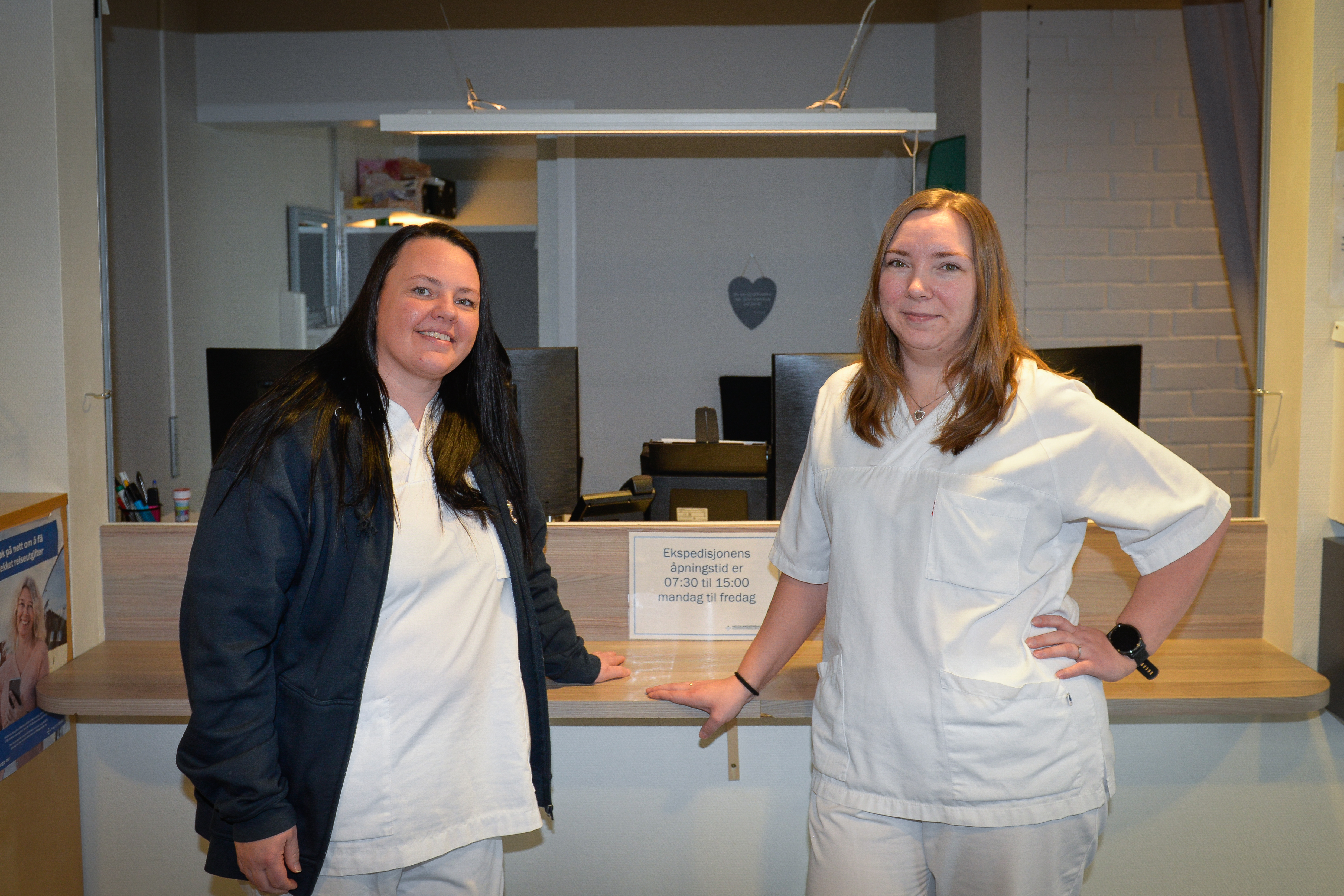 To damer i sykehusklær foran en resepsjon