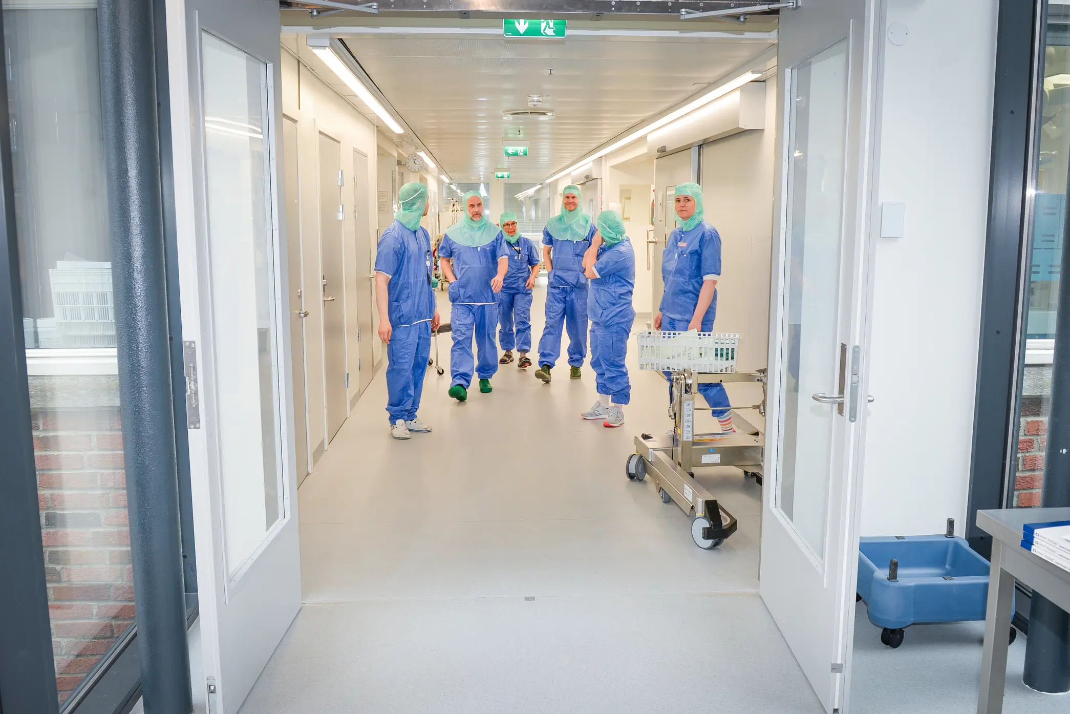 Seks operasjonskledte mennesker kommer gående i en gang