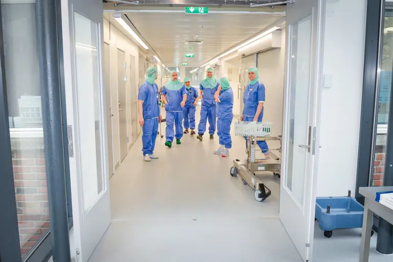 Seks operasjonskledte mennesker kommer gående i en gang