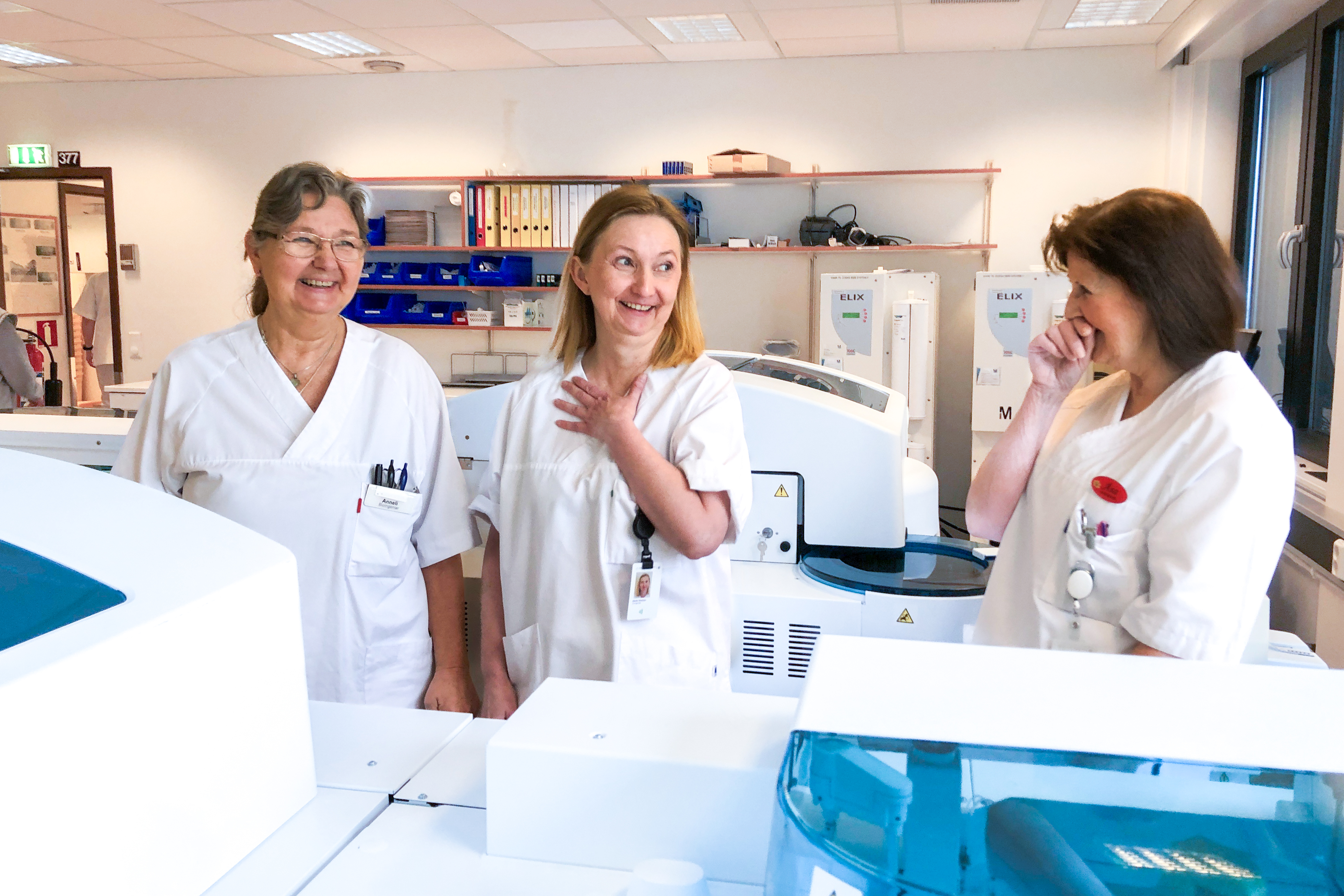 Tre damer ler i hvite klær