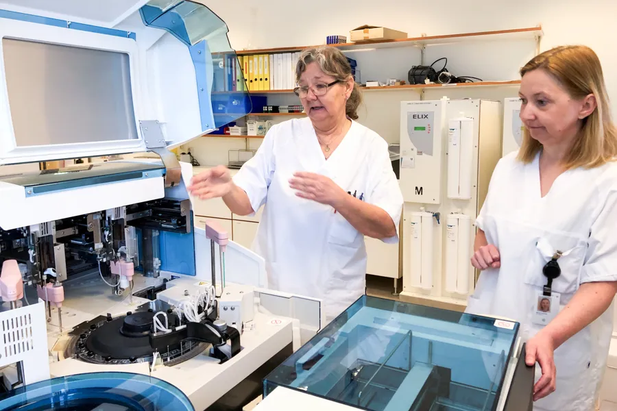 To damer i hvite klær peker mot noen maskiner