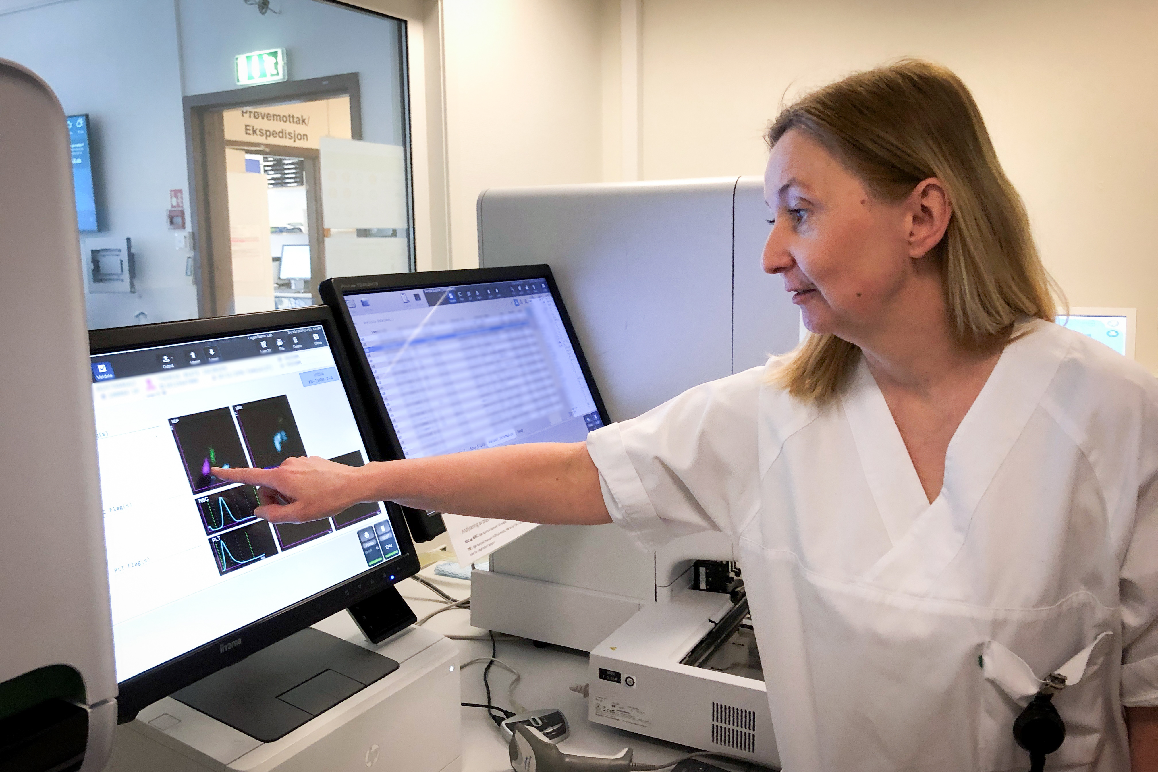 Hvitkledt dame peker på en skjerm