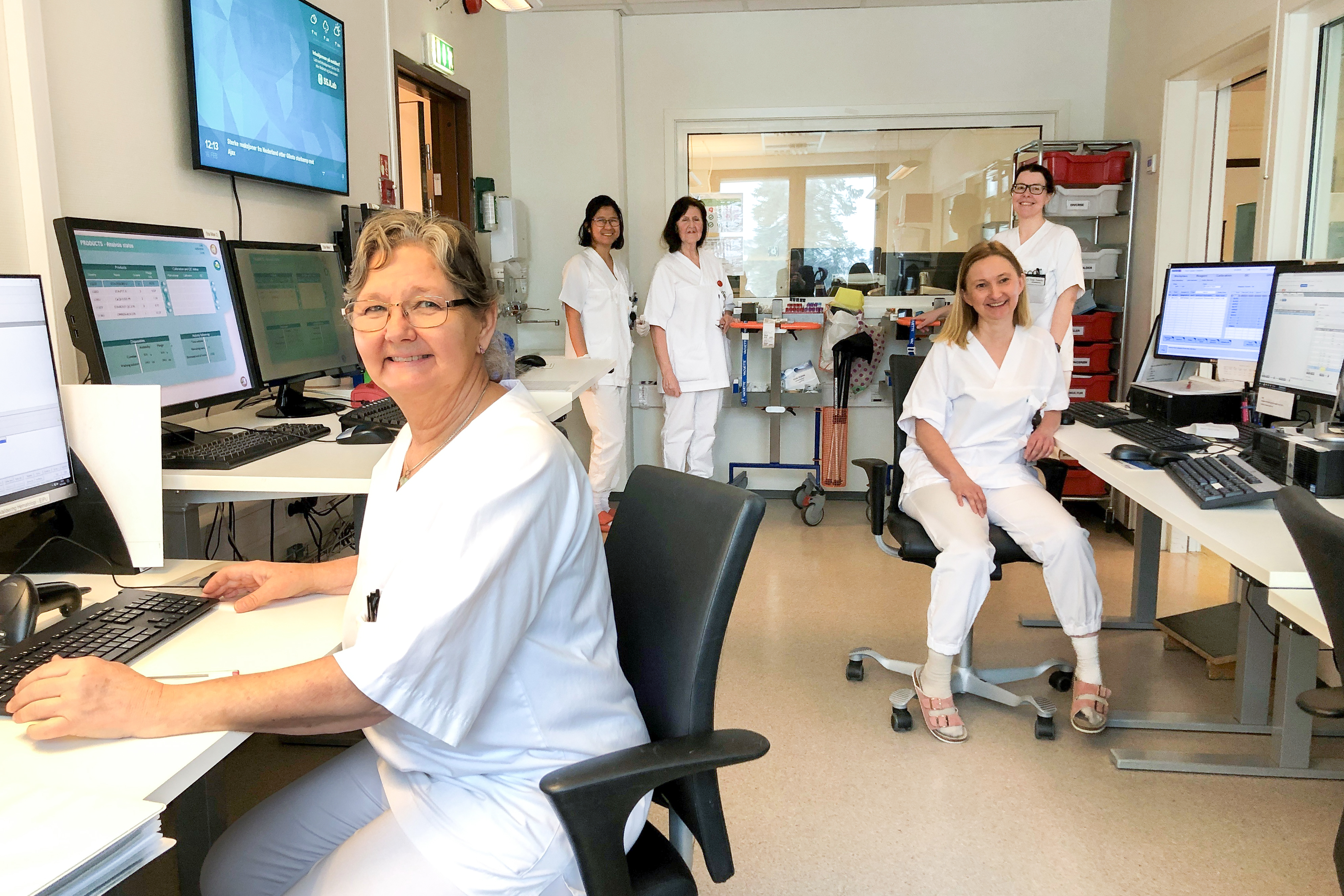 Fem hvitkledte kolleger i et stort rom