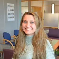 En dame med langt hår som smiler til kameraet