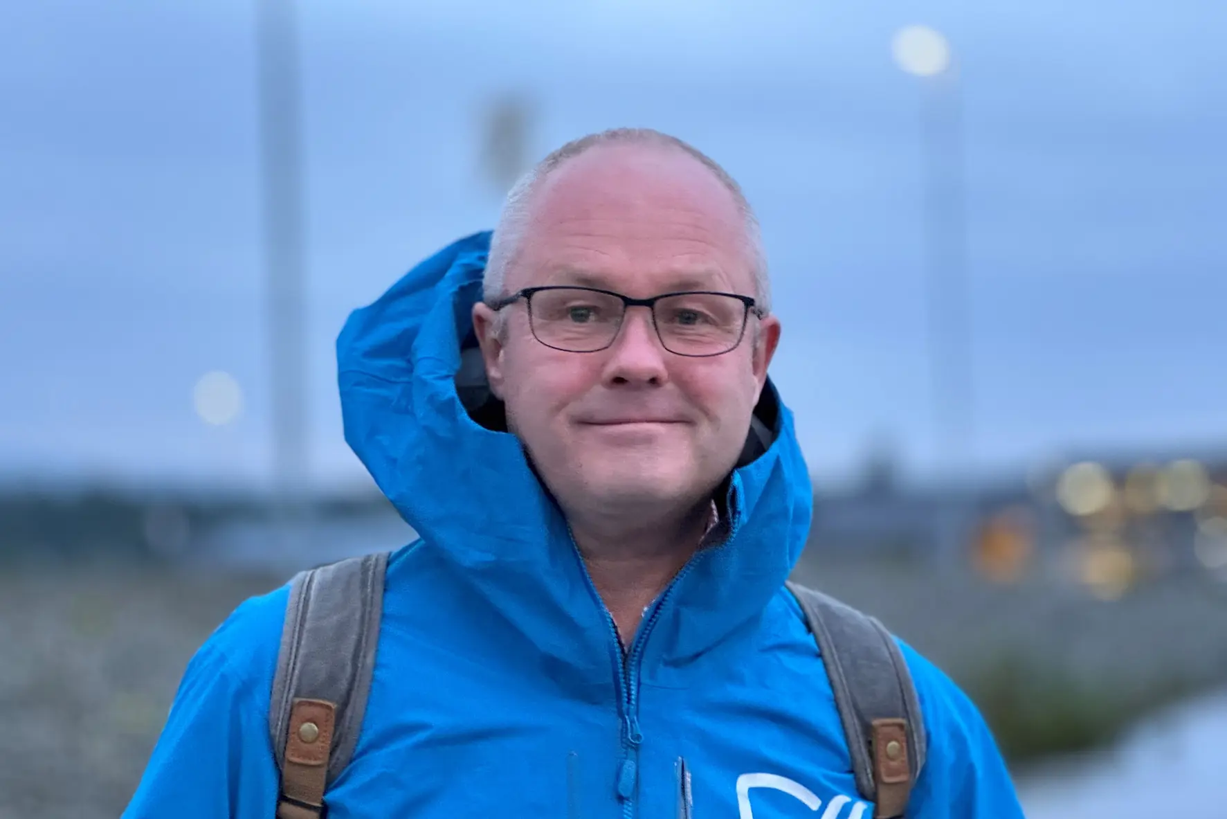 En mann med briller og en blå jakke med ryggsekk