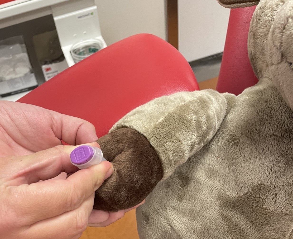 En person som tar blodprøve på en bamse