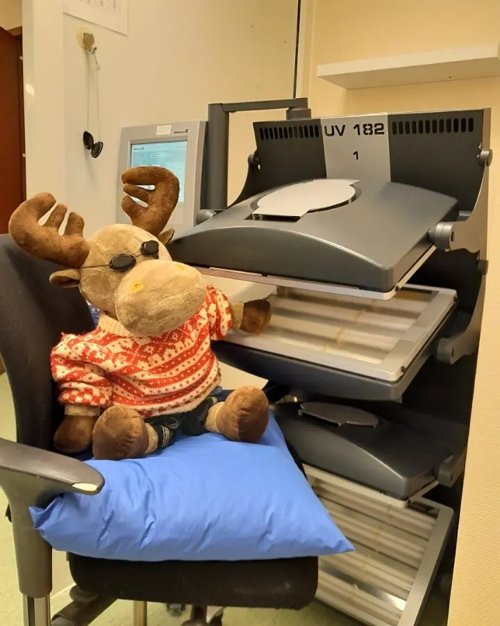 En teddybjørn som sitter i en stol og får lysbehandling