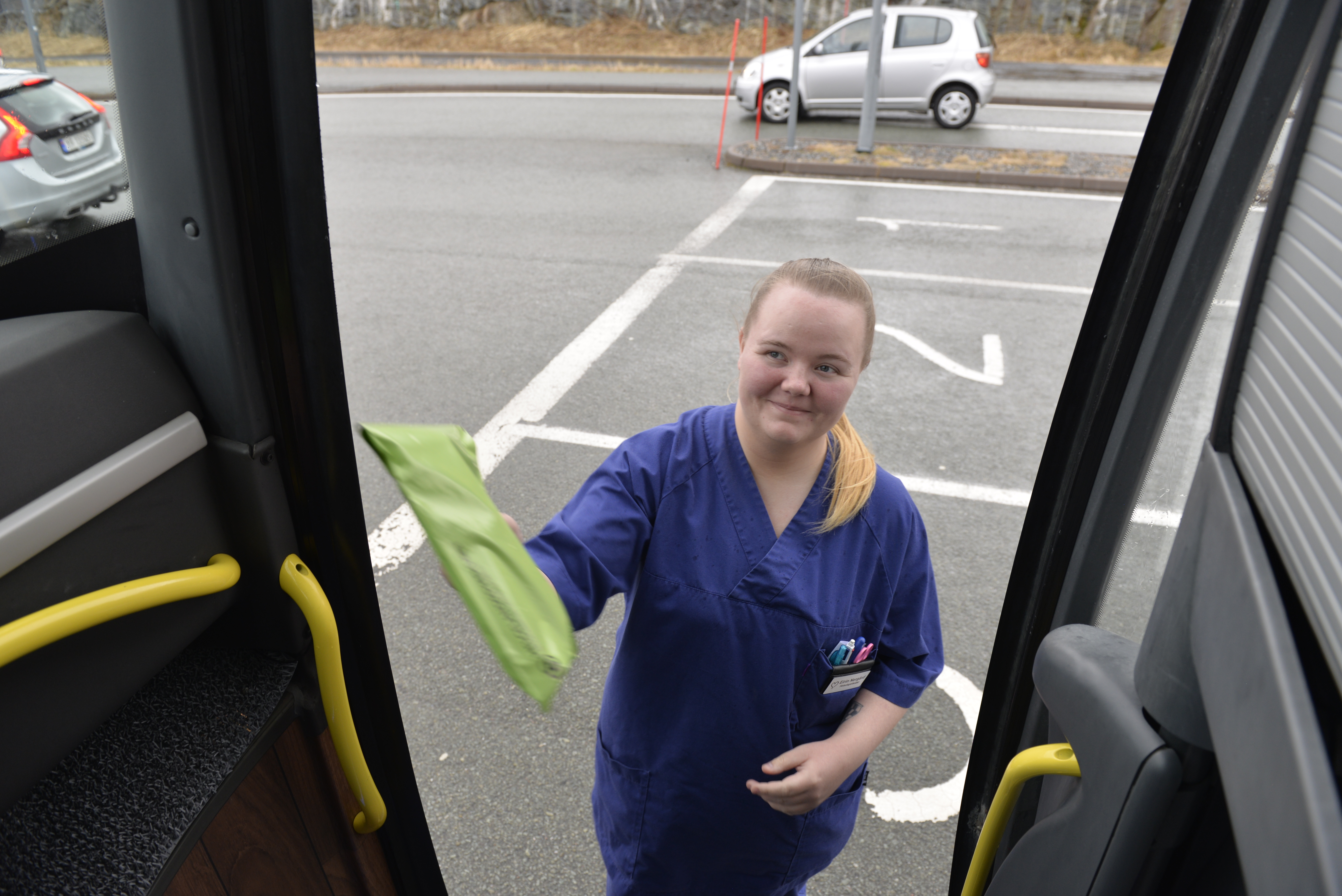 Dame strekker seg inn i bussen med en pakke