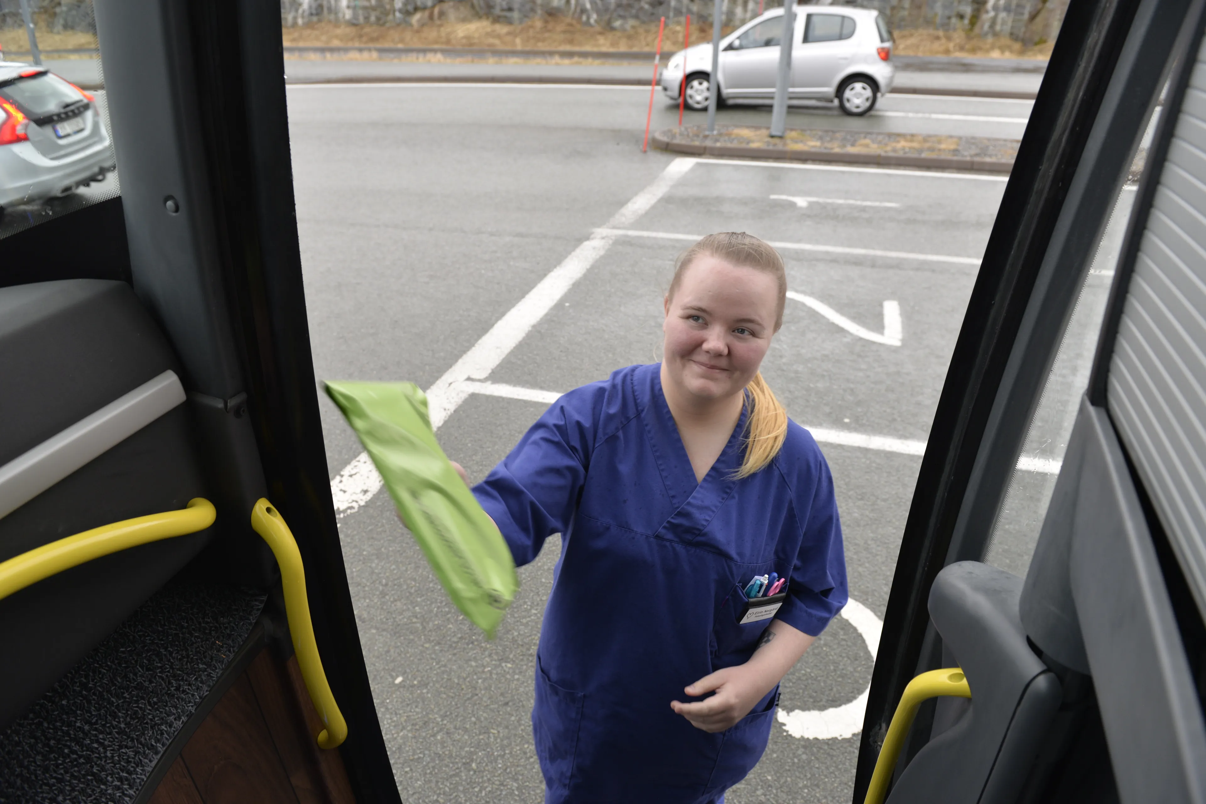 Dame strekker seg inn i bussen med en pakke