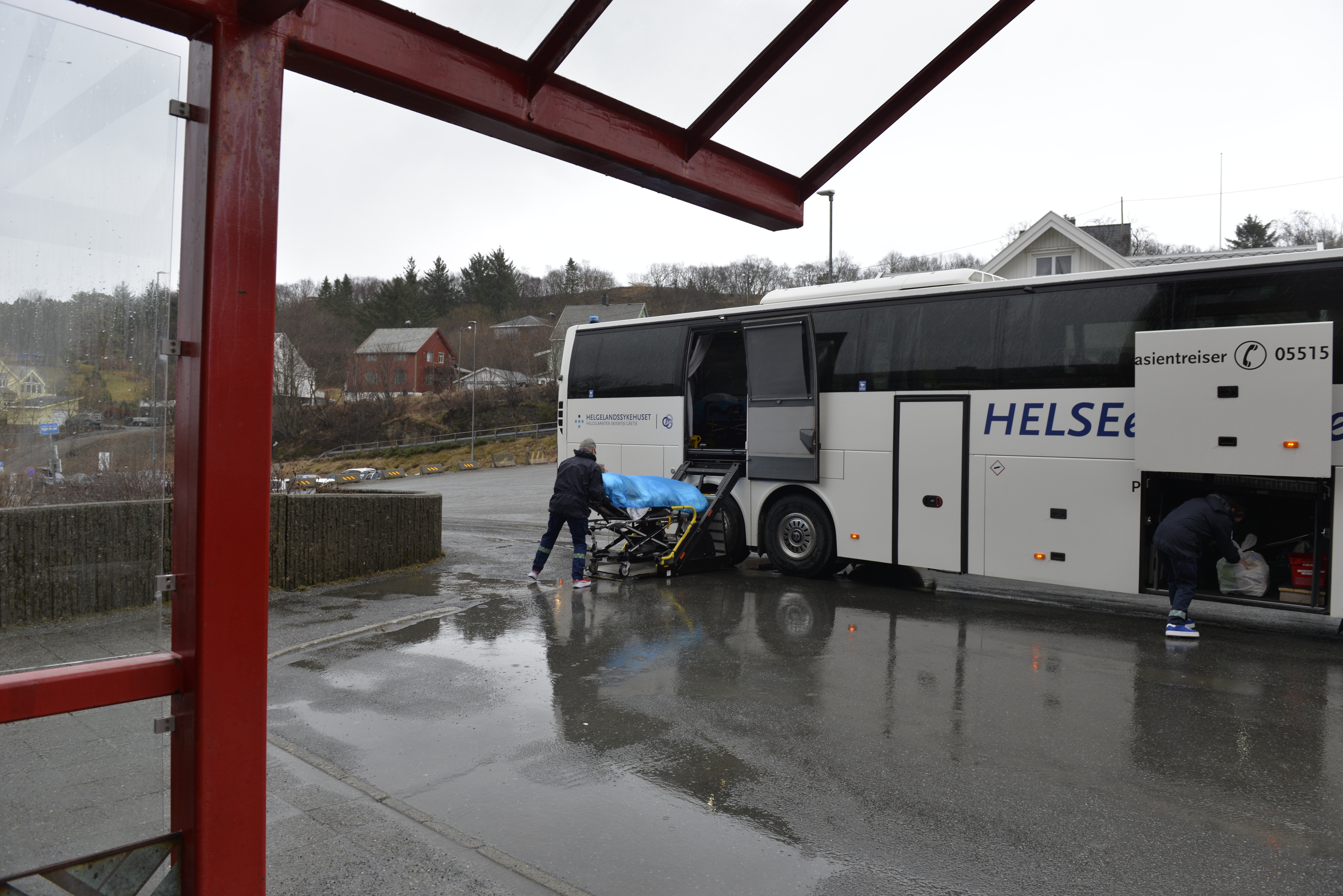 En pasient trilles på båre mot en buss