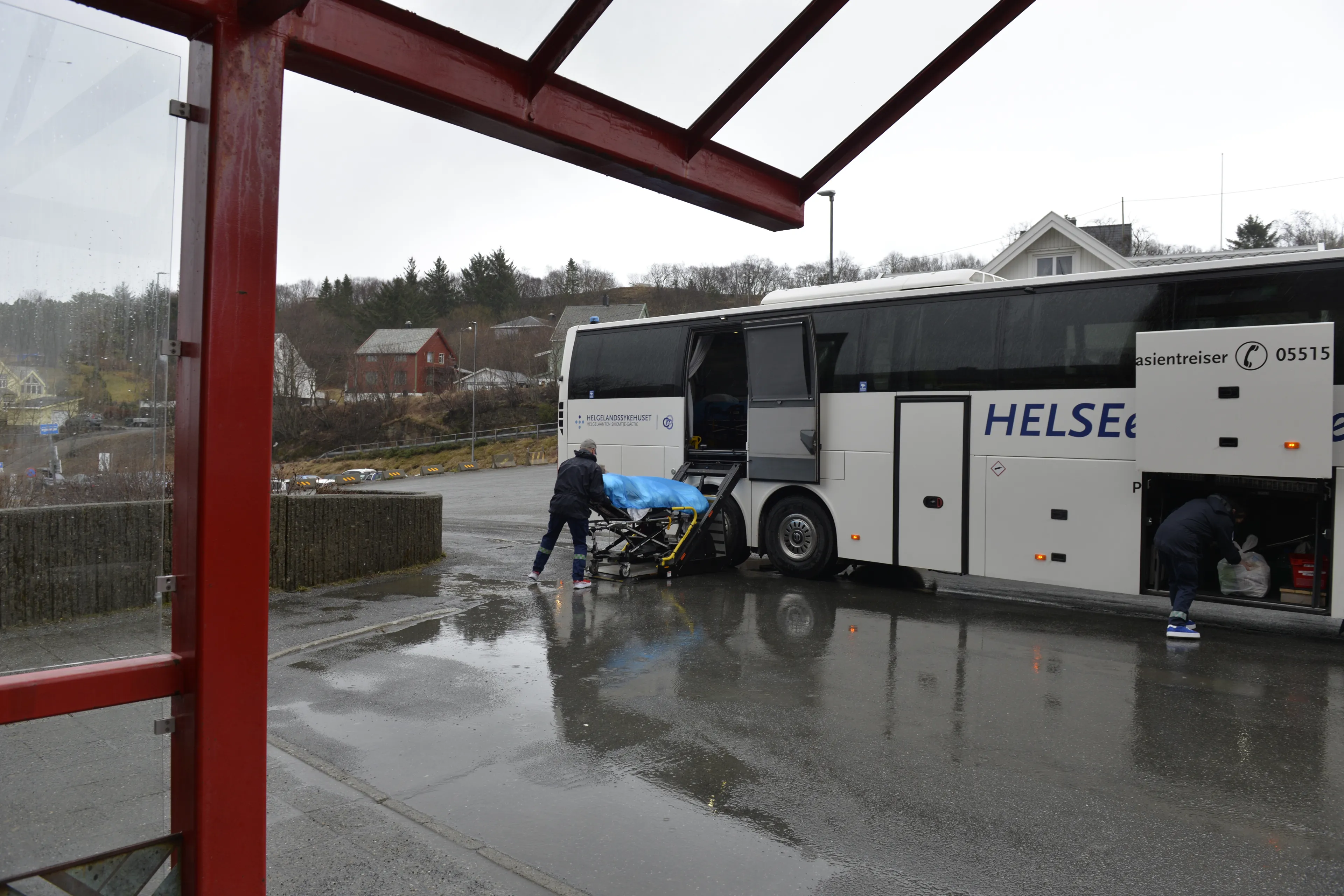 En pasient trilles på båre mot en buss