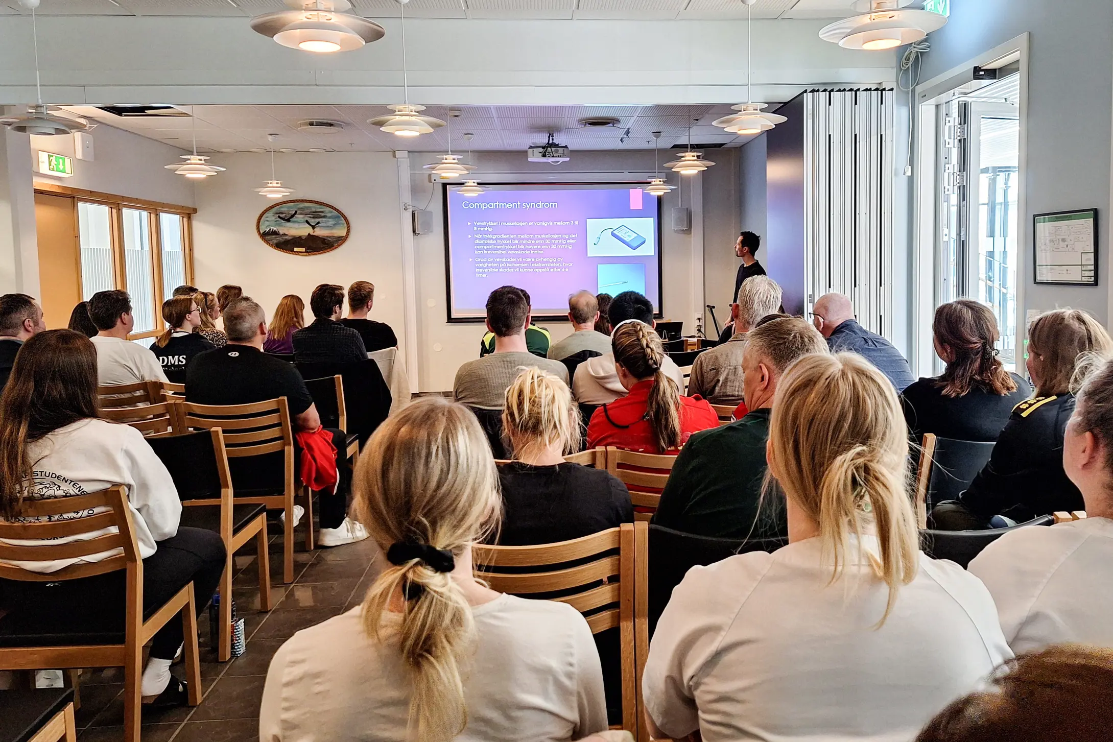 Ryggen på mange mennesker som sitter i en sal