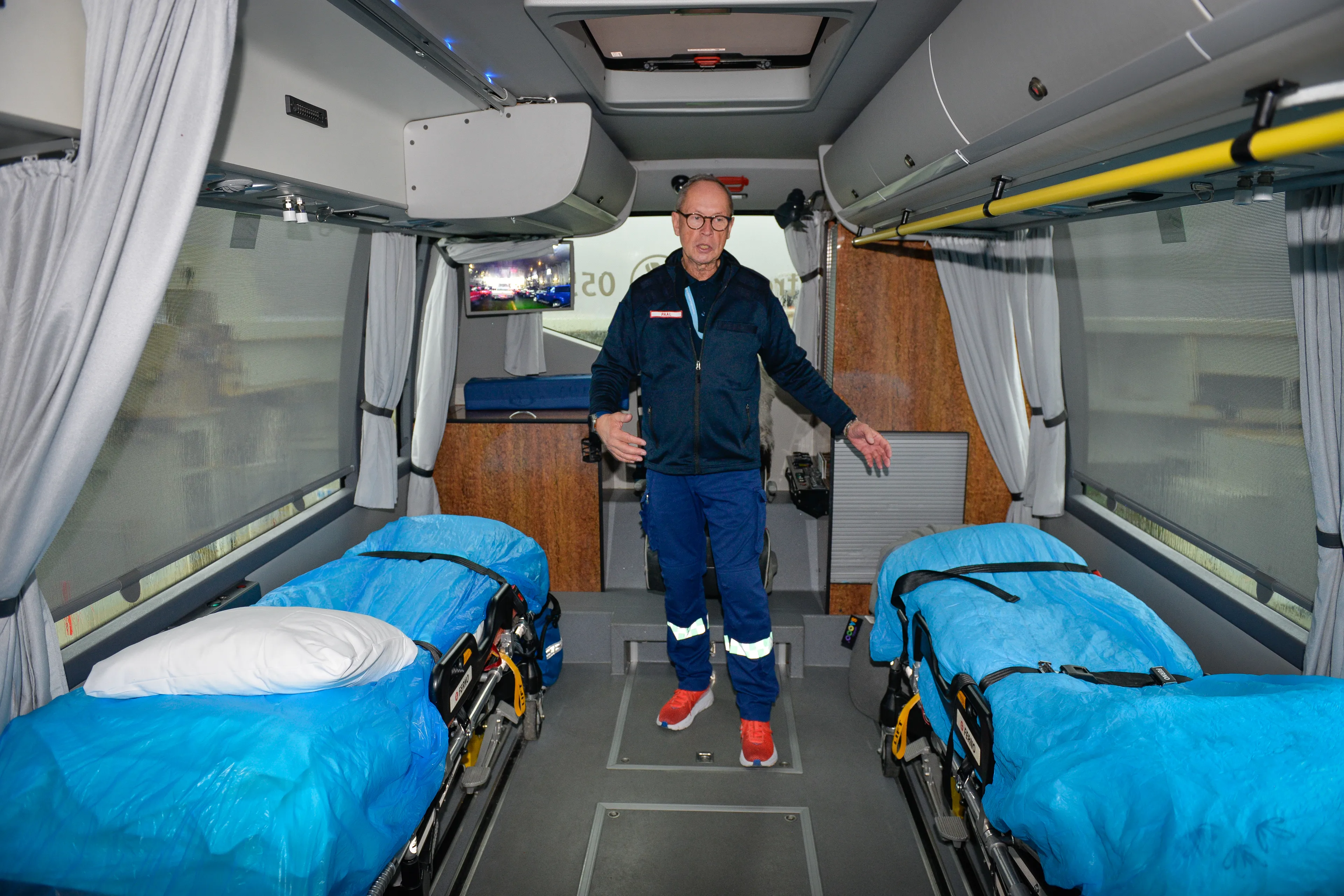 Mann står oppreis mellom to bårer i en buss