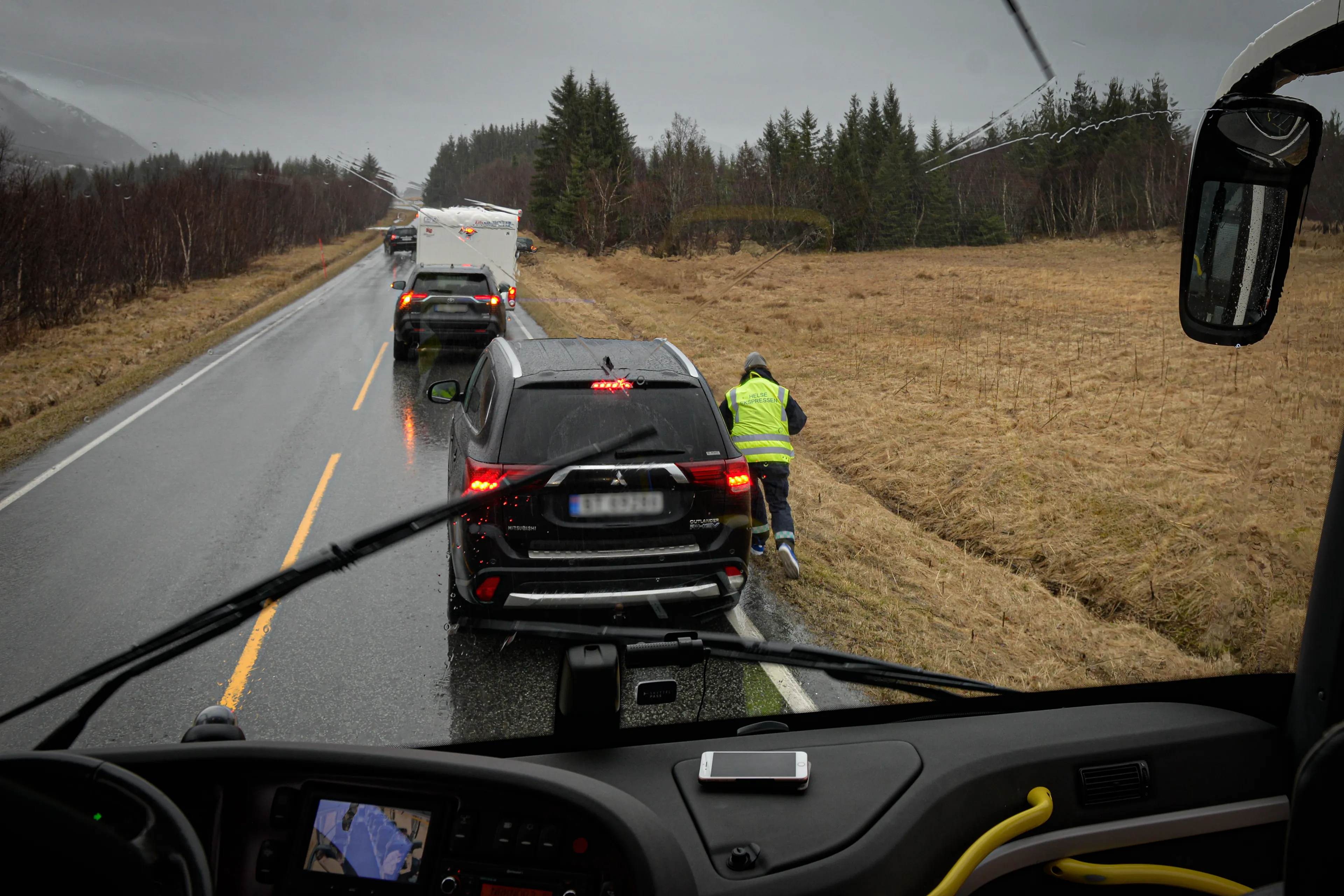 En dame med gul vest løper langs veikanten
