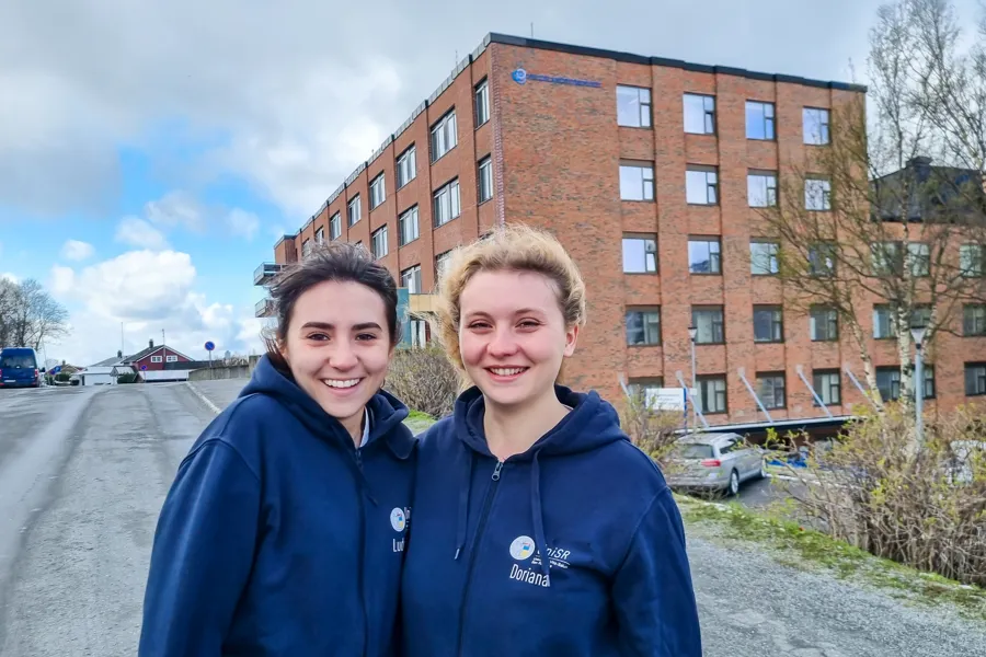 To kvinnelige studenter som poserer for et bilde foran en bygning