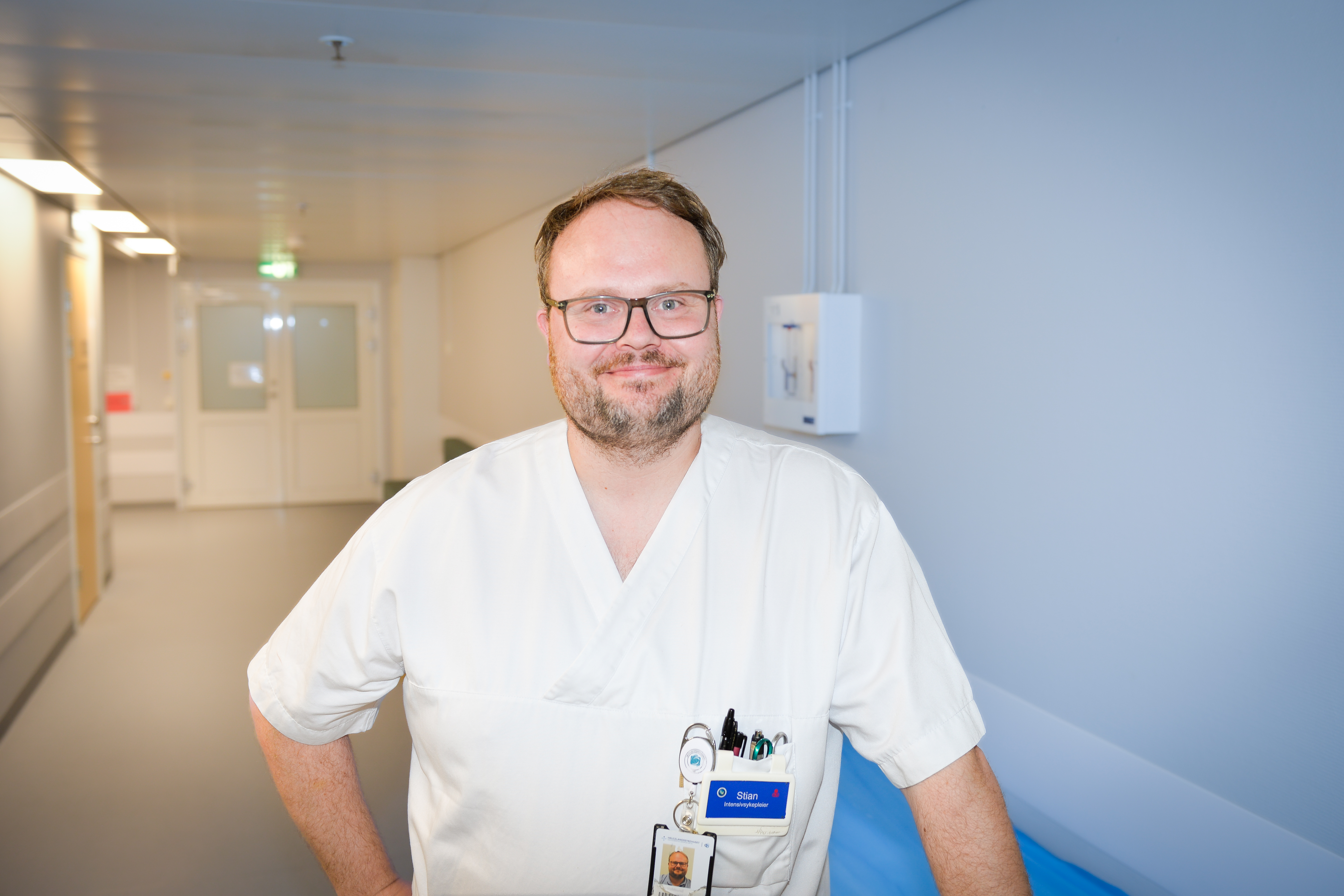 Mann med briller i hvite sykehusklær