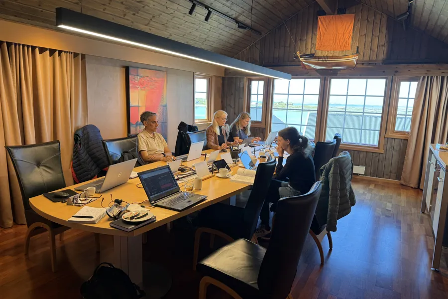 En gruppe personer sitter på et møterom med sine laptoper