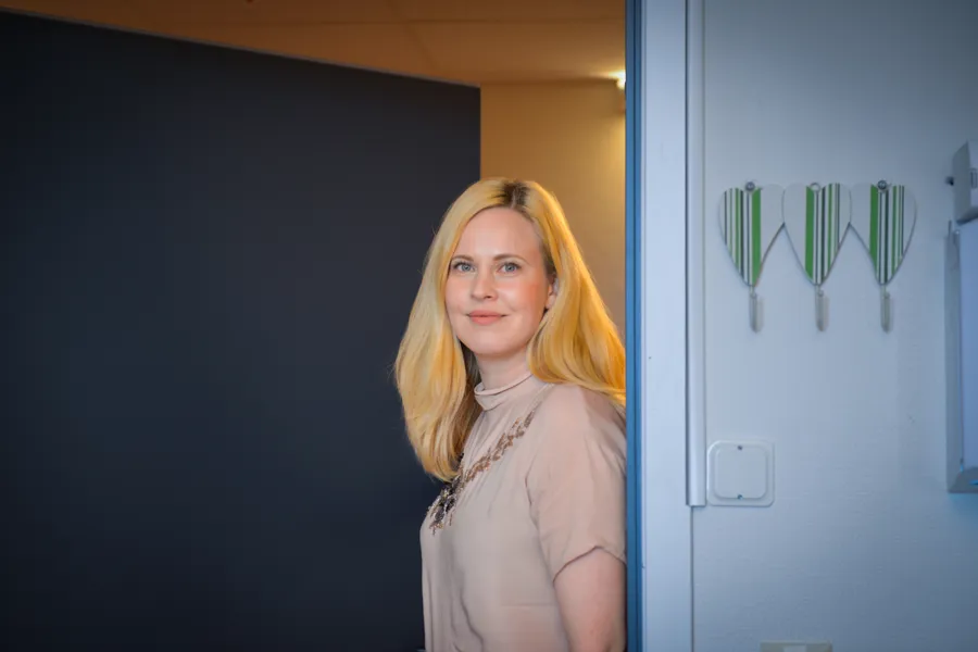 Dame med lyst hår kommer inn i et rom