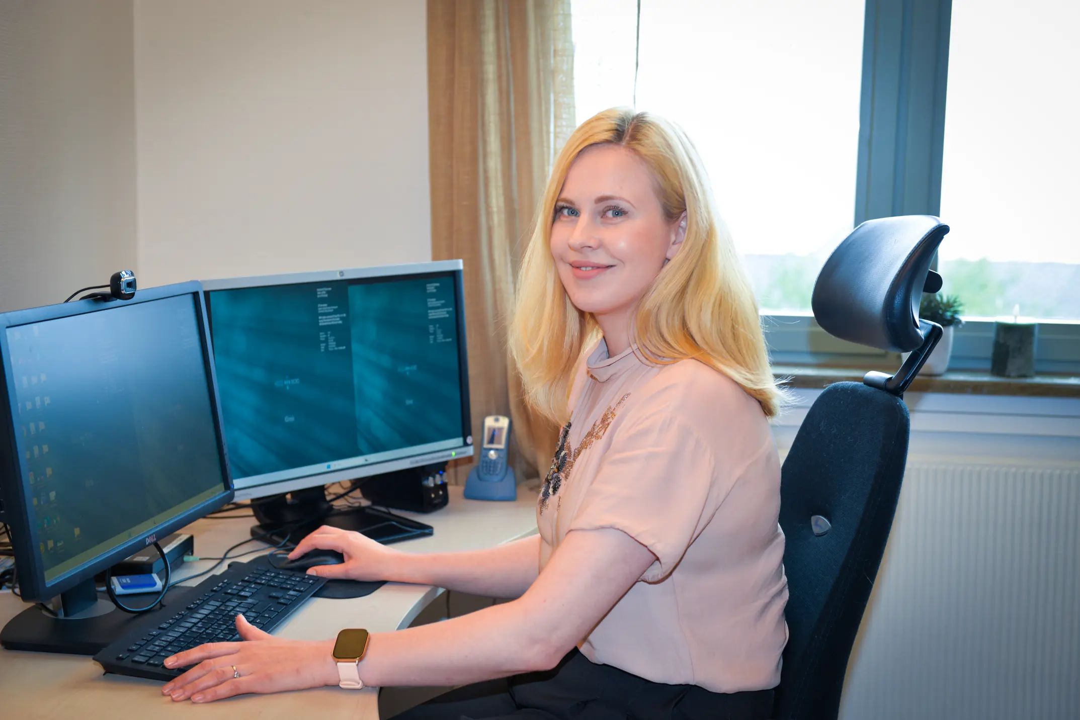 Dame med lyst, langt hår sitter ved kontorpulten sin