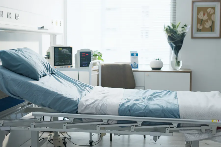 En sykehusseng med skrivebord og stol