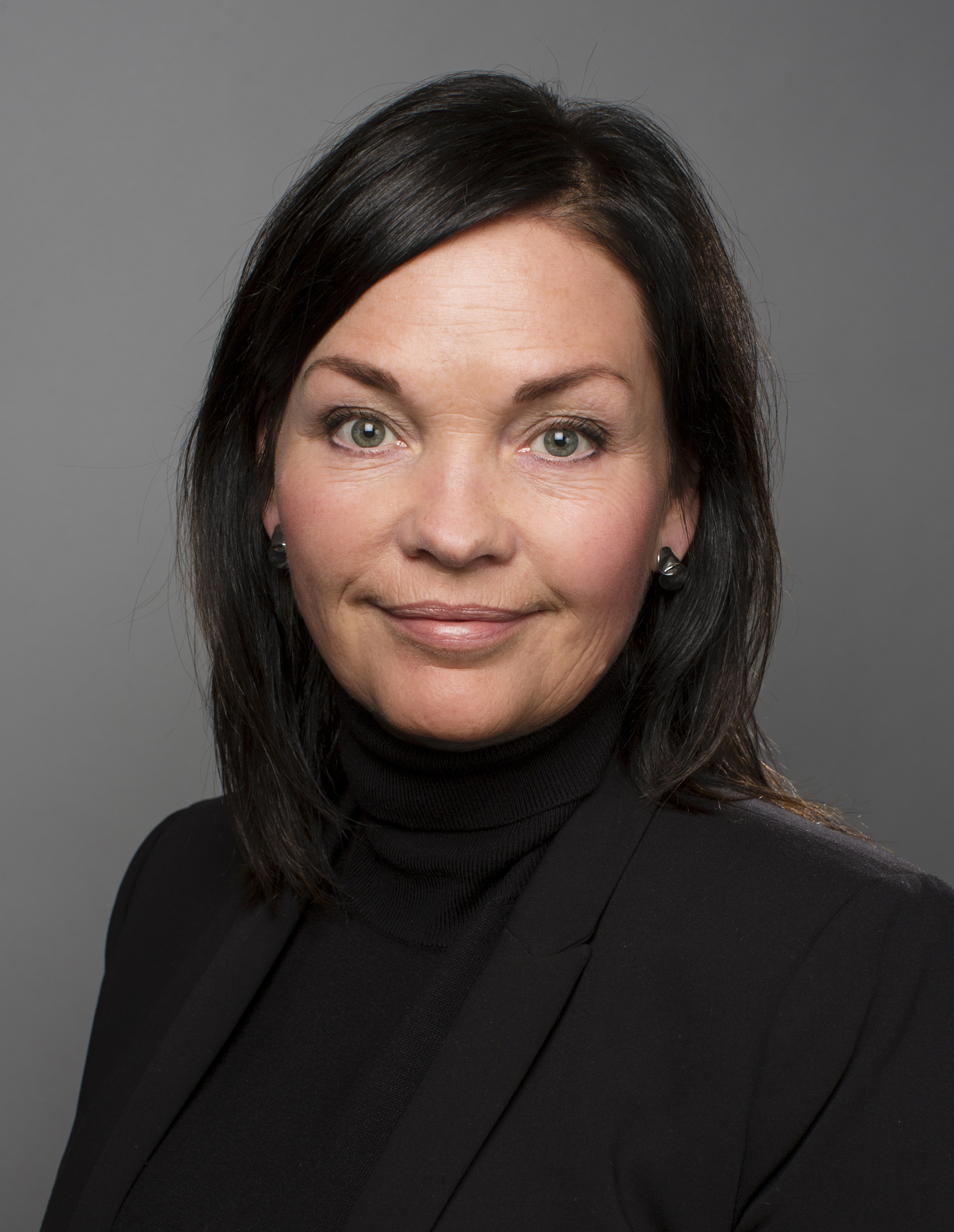 Dame med svart hår ser inn i kameraet