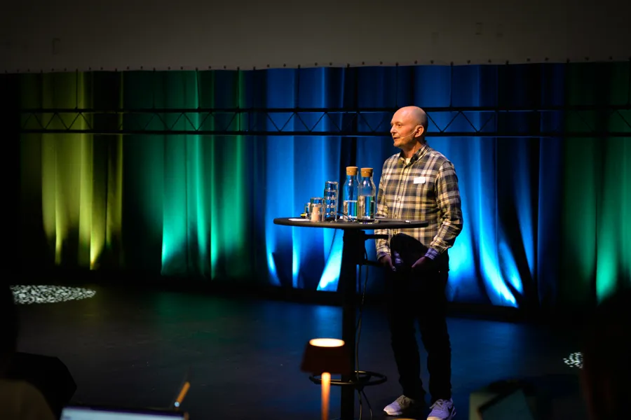 En mann som står på en scene og snakker i en mikrofon