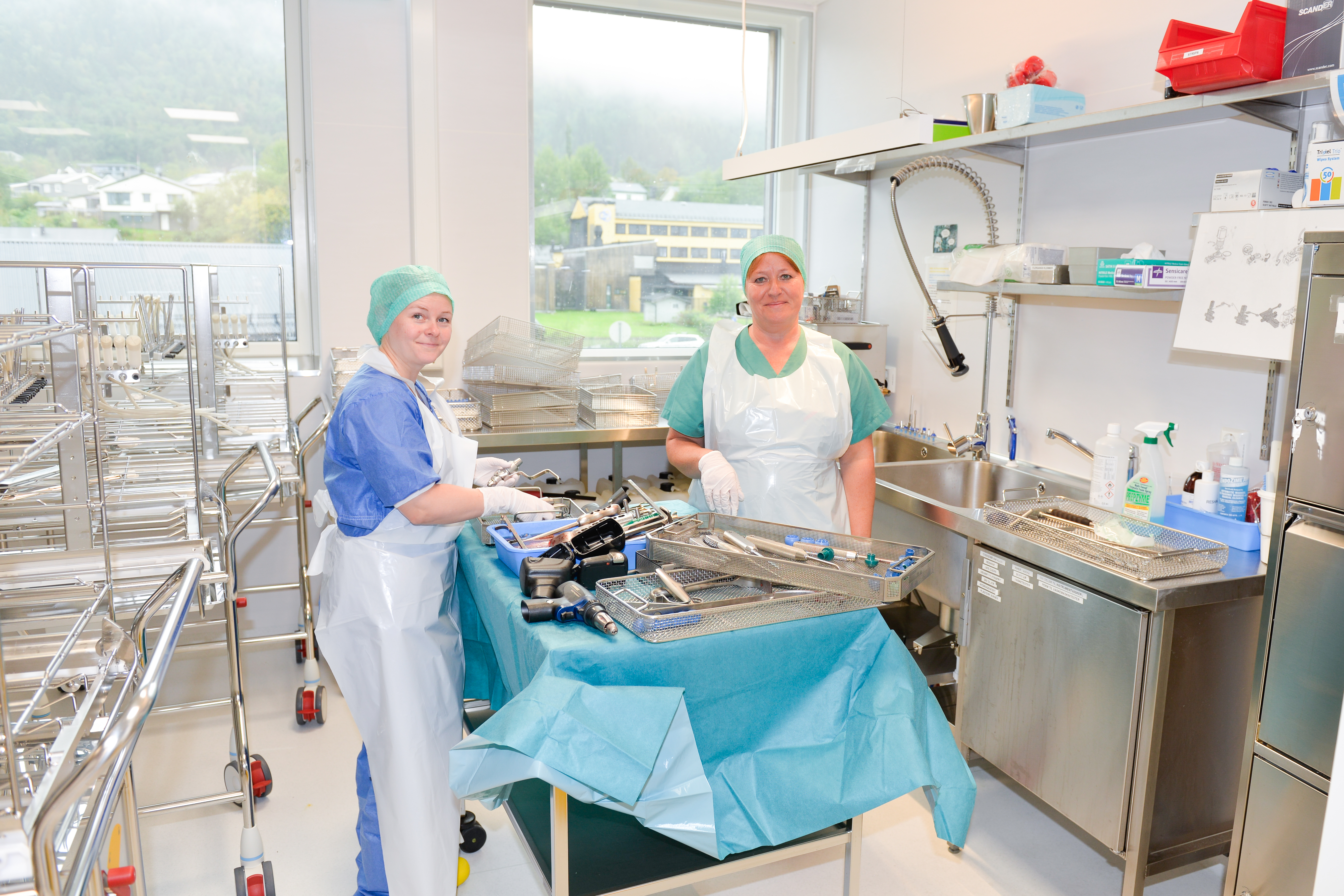 To damer står i det ene rommet til Sterilsentralen. På bordet ligger mye operasjonsutstyr