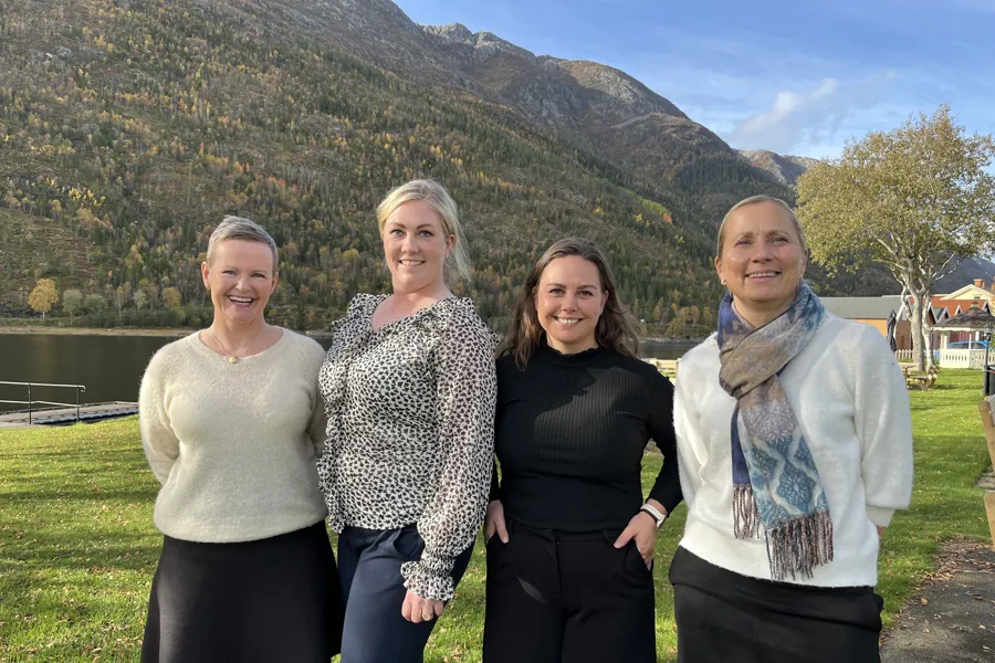 Fire damer poserer for et bilde på en plen