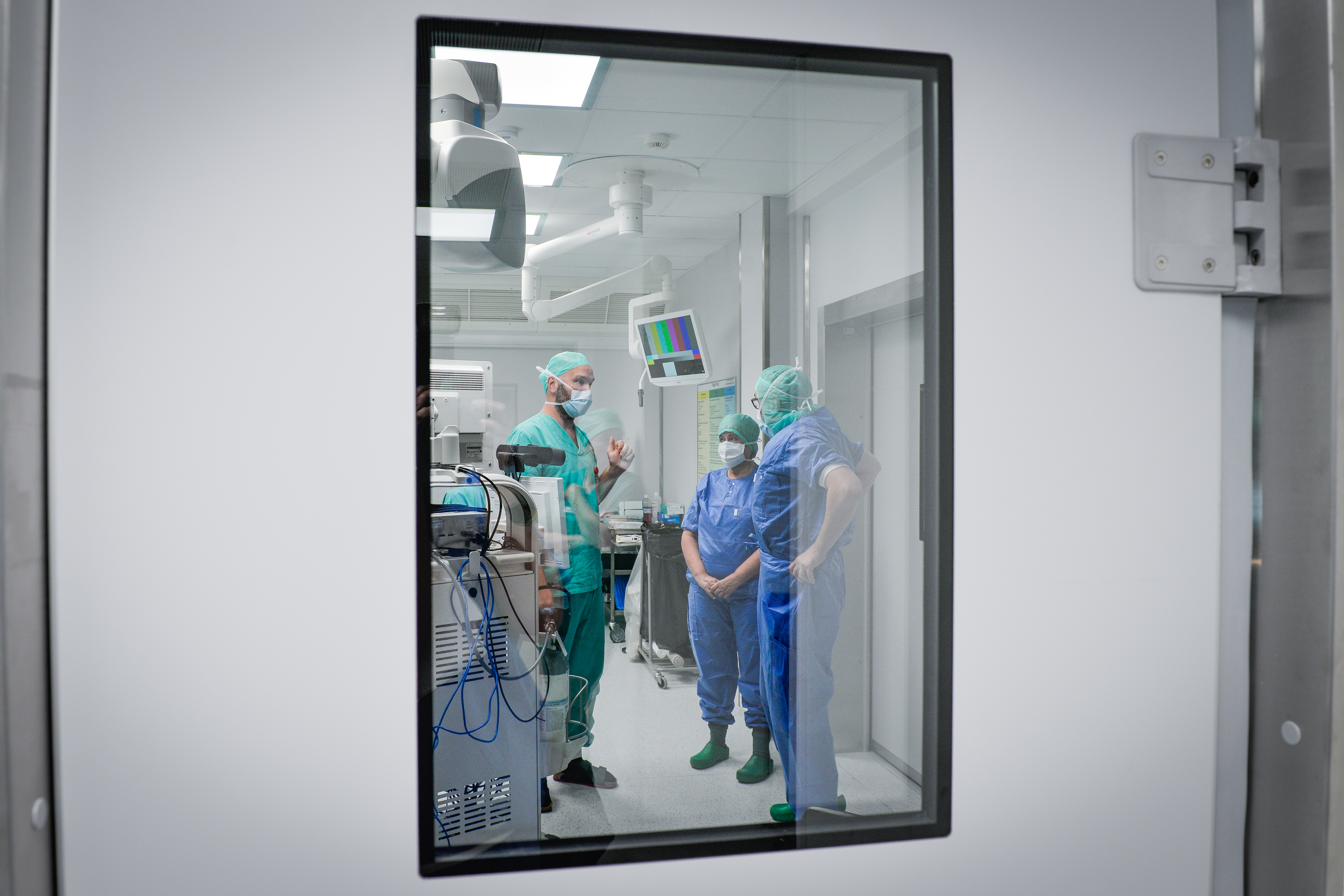 Tre personer i sykehusklær snakker med hverandre