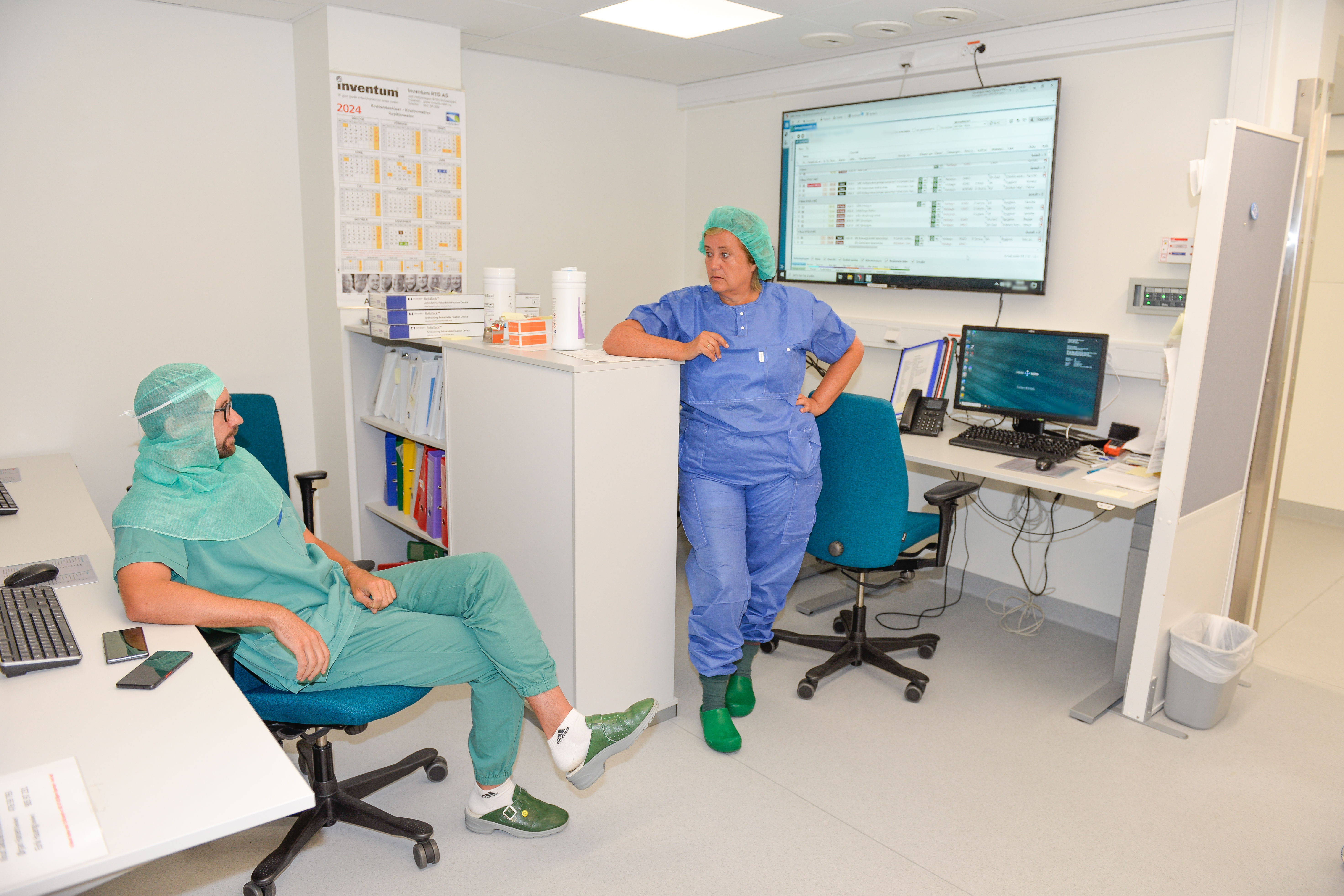 En sykehuskledt mannlig ortoped snakker med en blåkledt kvinne