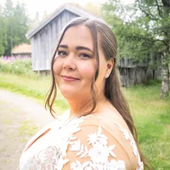 En dame i hvit kjole og langt hår snur seg mot kamera