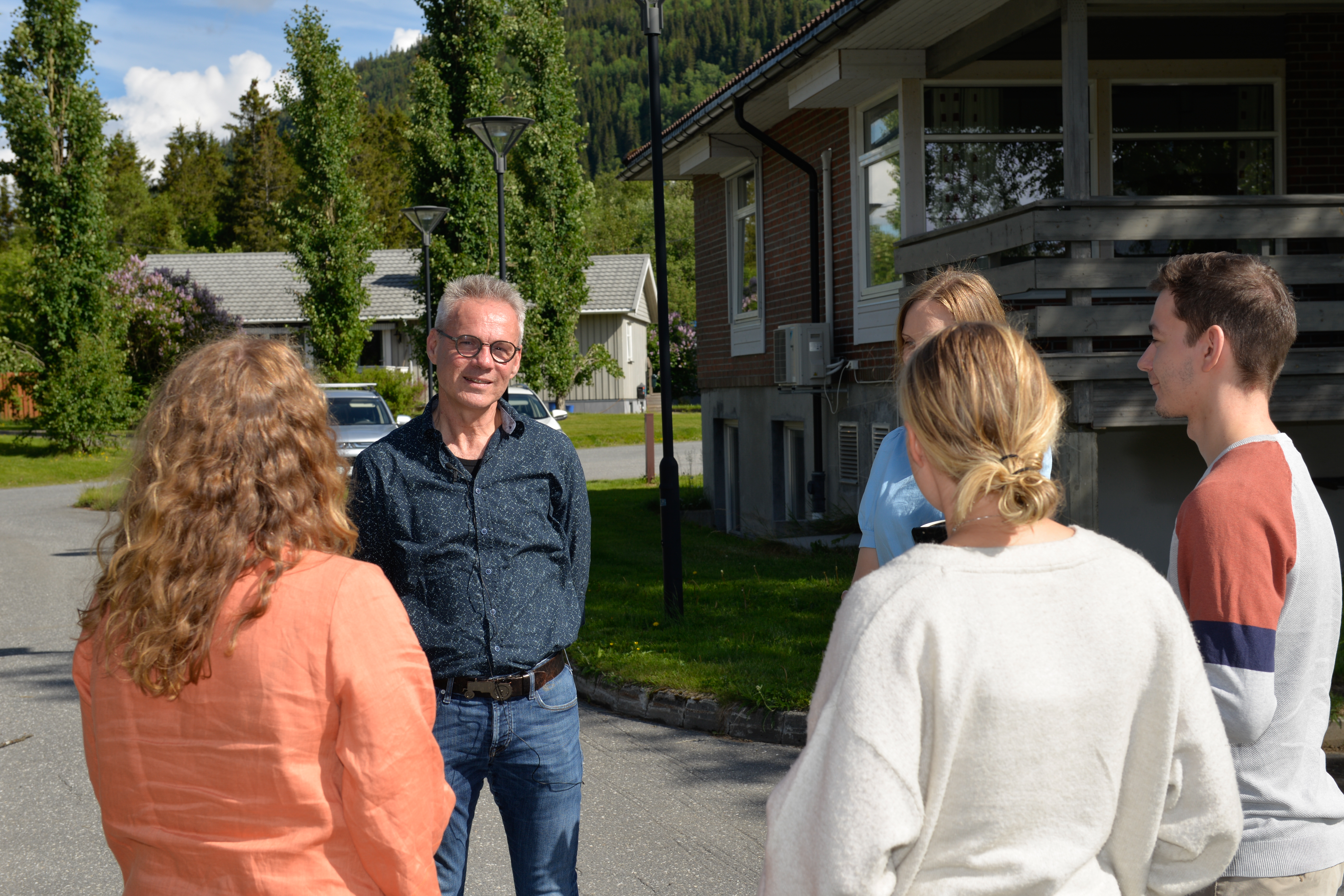 Fem kolleger står ute i sola og har en pause