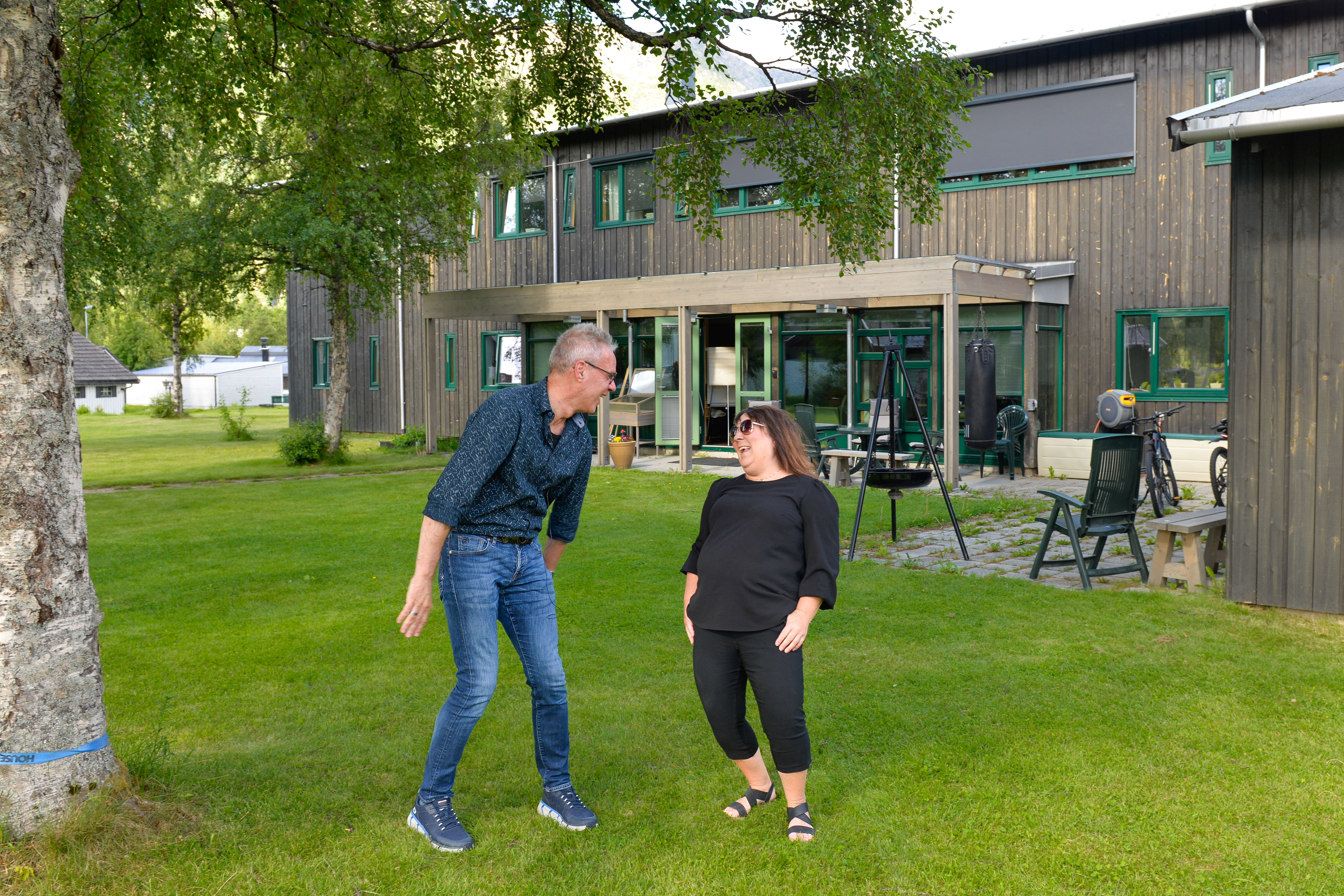 En mann og en dame står ute på plenen og ler hjertelig