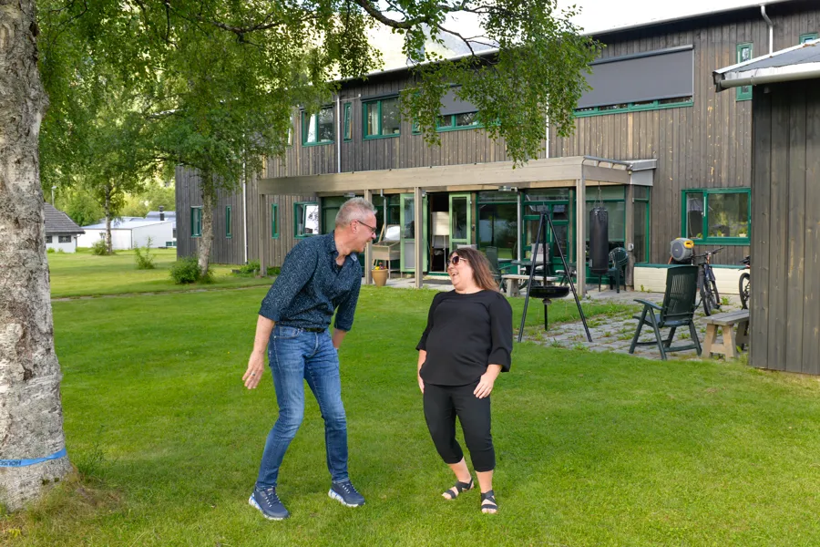 En mann og en dame står ute på plenen og ler hjertelig