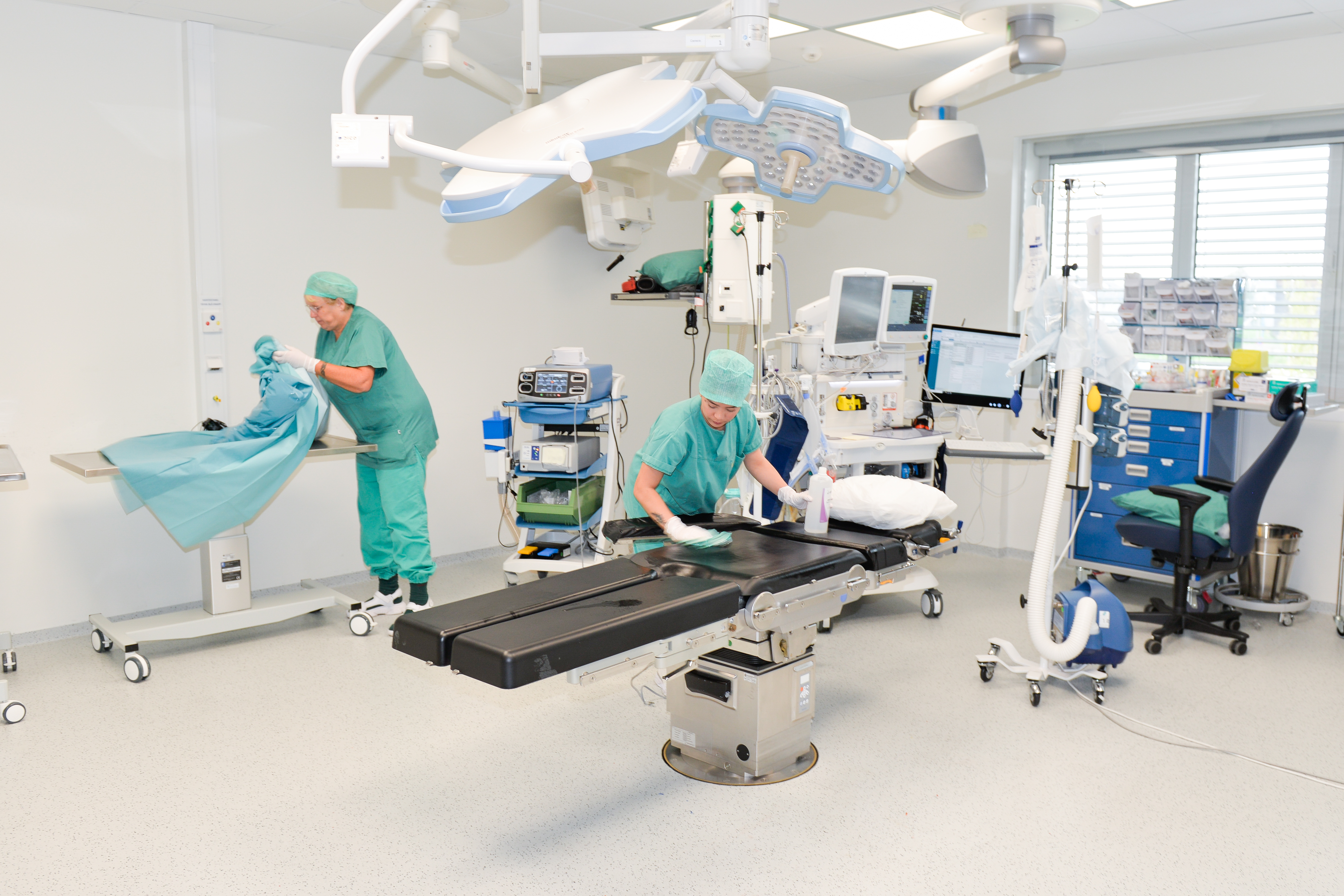 To damer vasker og klargjør ei operasjonsstue til neste operasjon