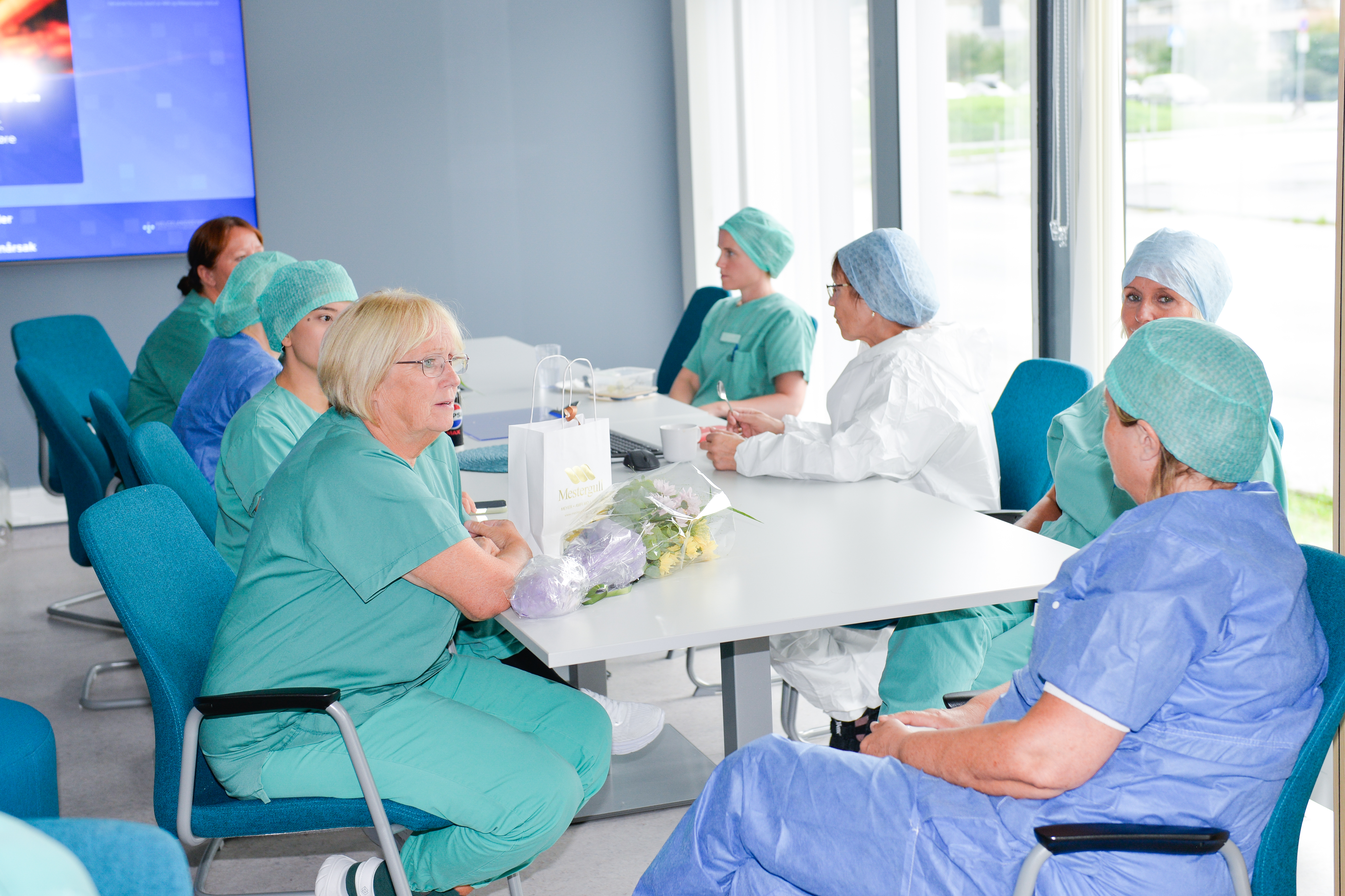 Mange personer sitter rundt et bord og snakker
